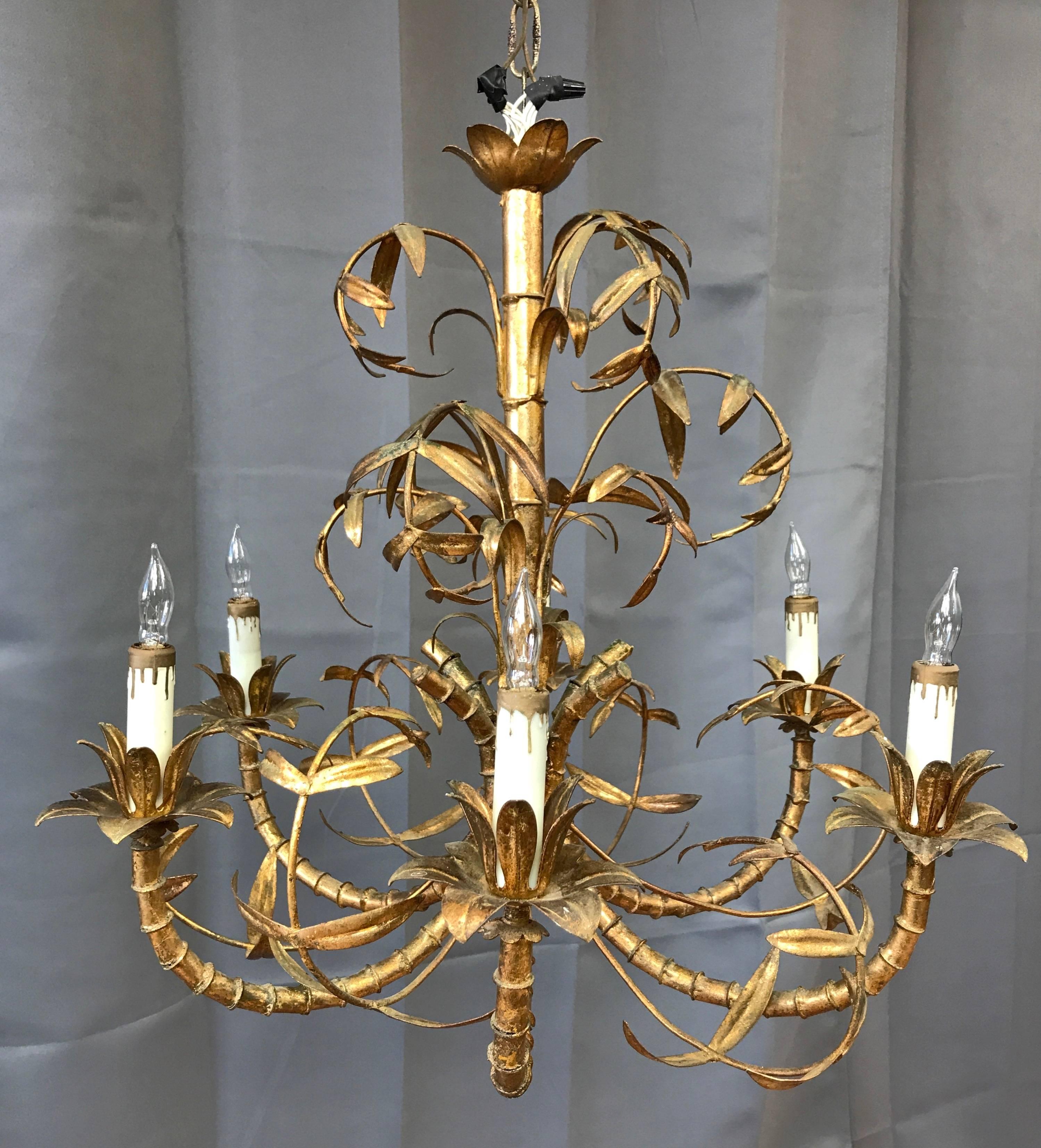 An elegant and enchanting Italian Mid-Century chinoiserie faux bamboo six-light chandelier with gold leaf finish.

Artistically rendered faux bamboo metal shaft and arms sprout delicate and detailed foliage that’s exquisitely executed. Gold leaf