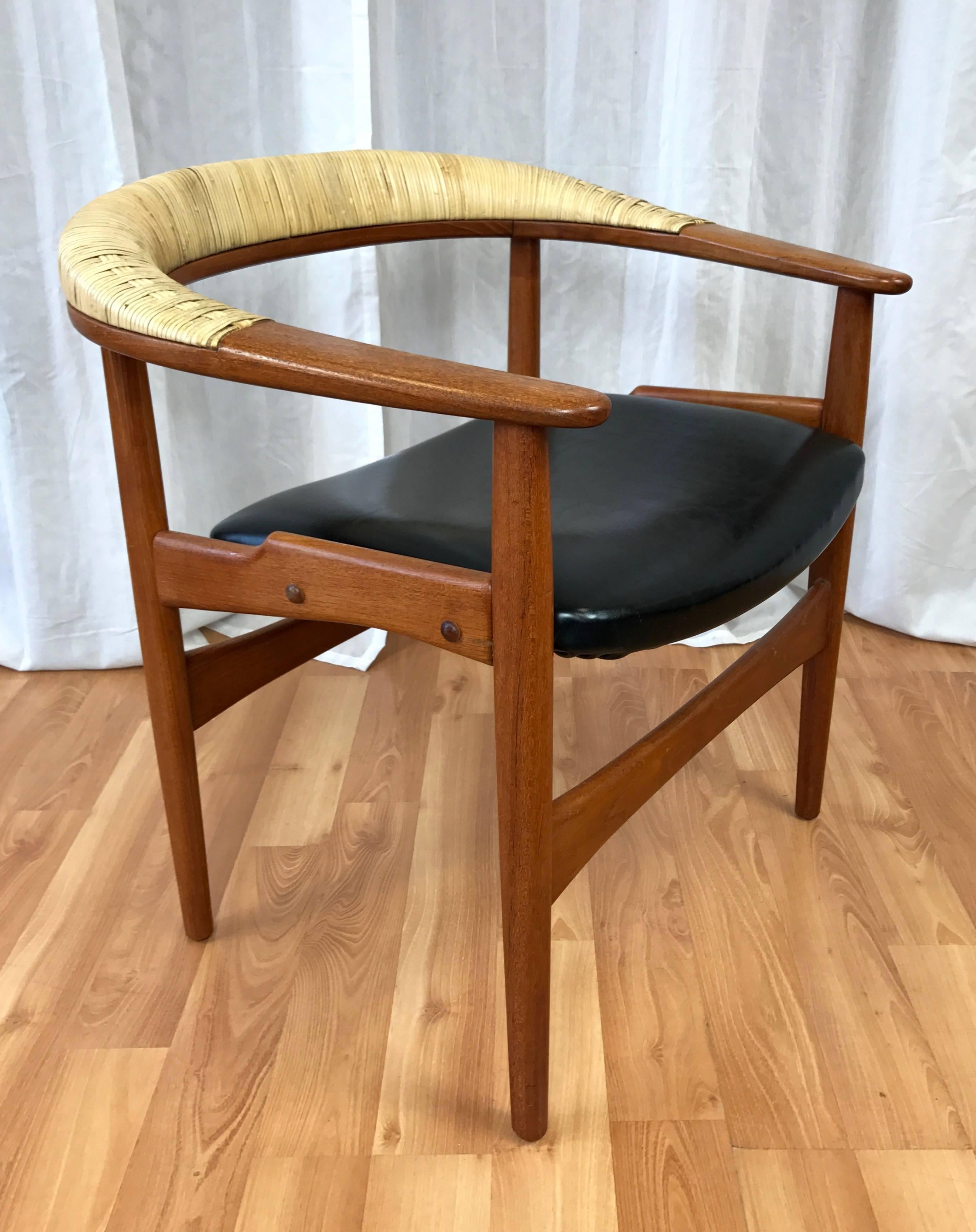 A rare Danish Modern teak armchair with cane-wrapped back and faux-leather seat by Arne Hovmand-Olsen.

Wide teak frame is defined by a substantial sweeping backrest inset with original wrapped and woven natural cane. Generous seat is upholstered