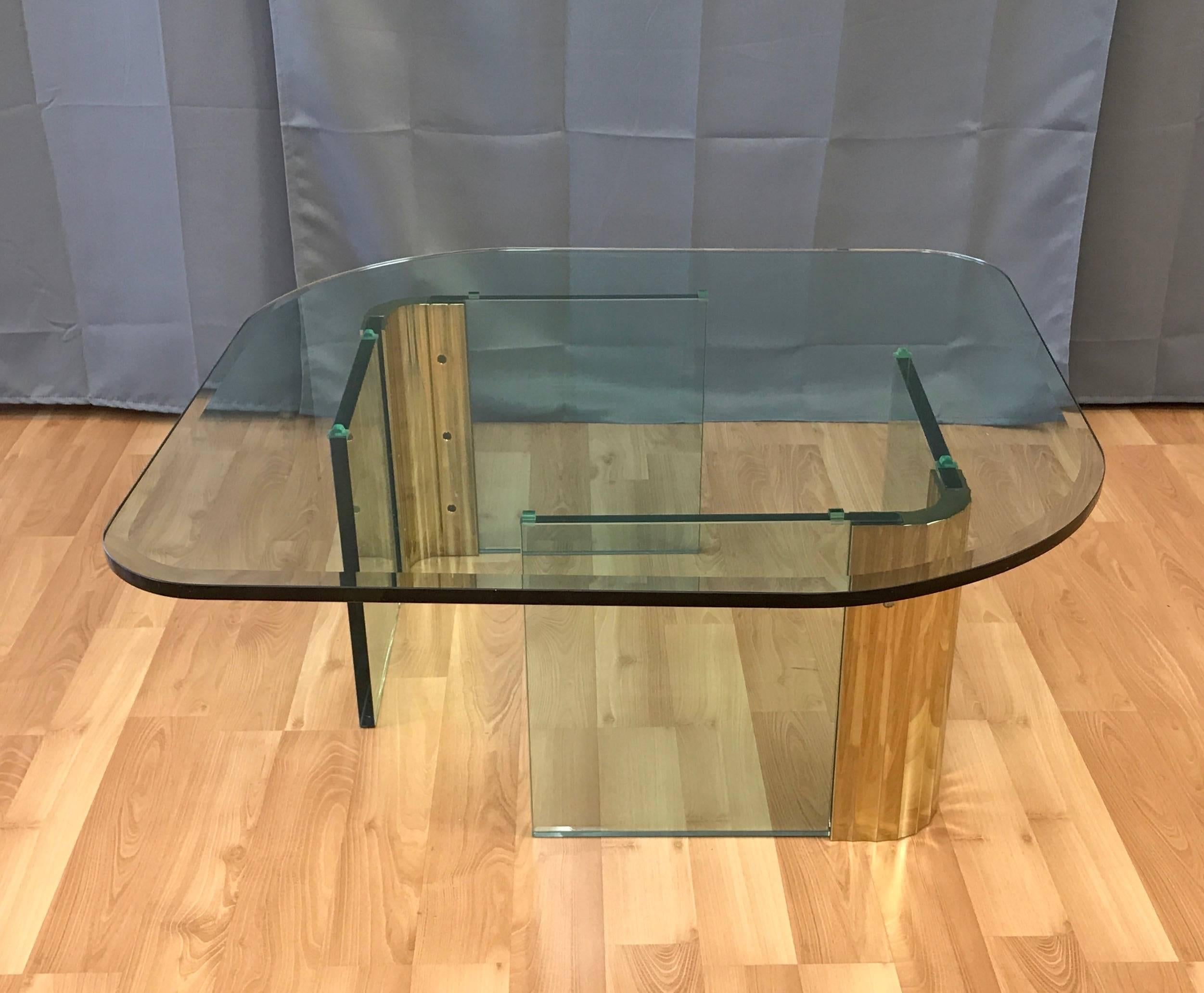 A large and uncommon coffee or cocktail table with brass and glass base and thick asymmetrical glass top that's very much in the style of Leon Rosen's work for Pace Collection.

Base comprised of a pair of free-standing scalloped brass architectural