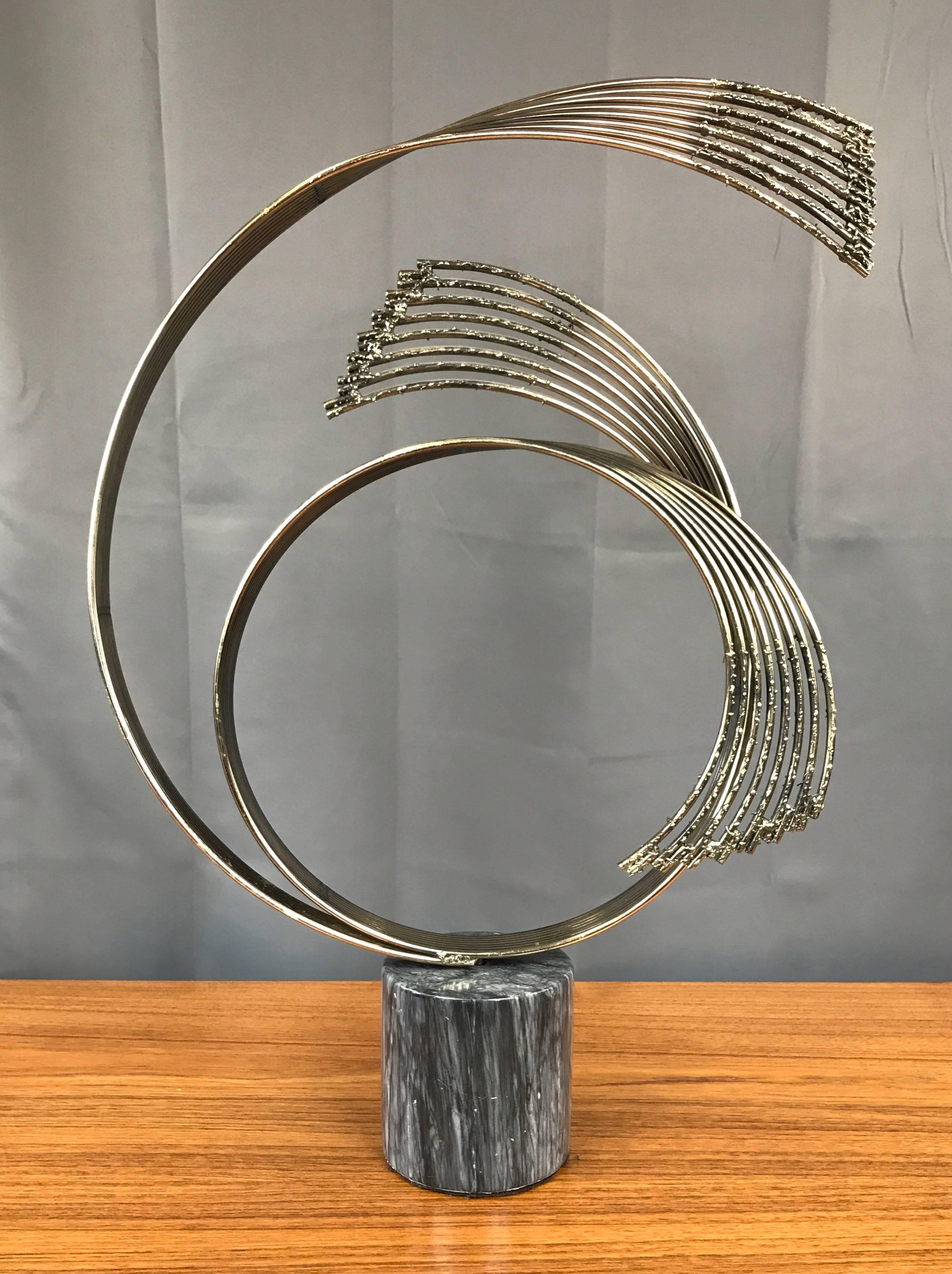 A large and dramatic signed brass sculpture on marble pedestal titled “Windswept” by Curtis Jeré.

Three looping sets of eight welded brass rods transition from smooth, tightly grouped ribbons to gracefully spreading, Brutalist-style ends.