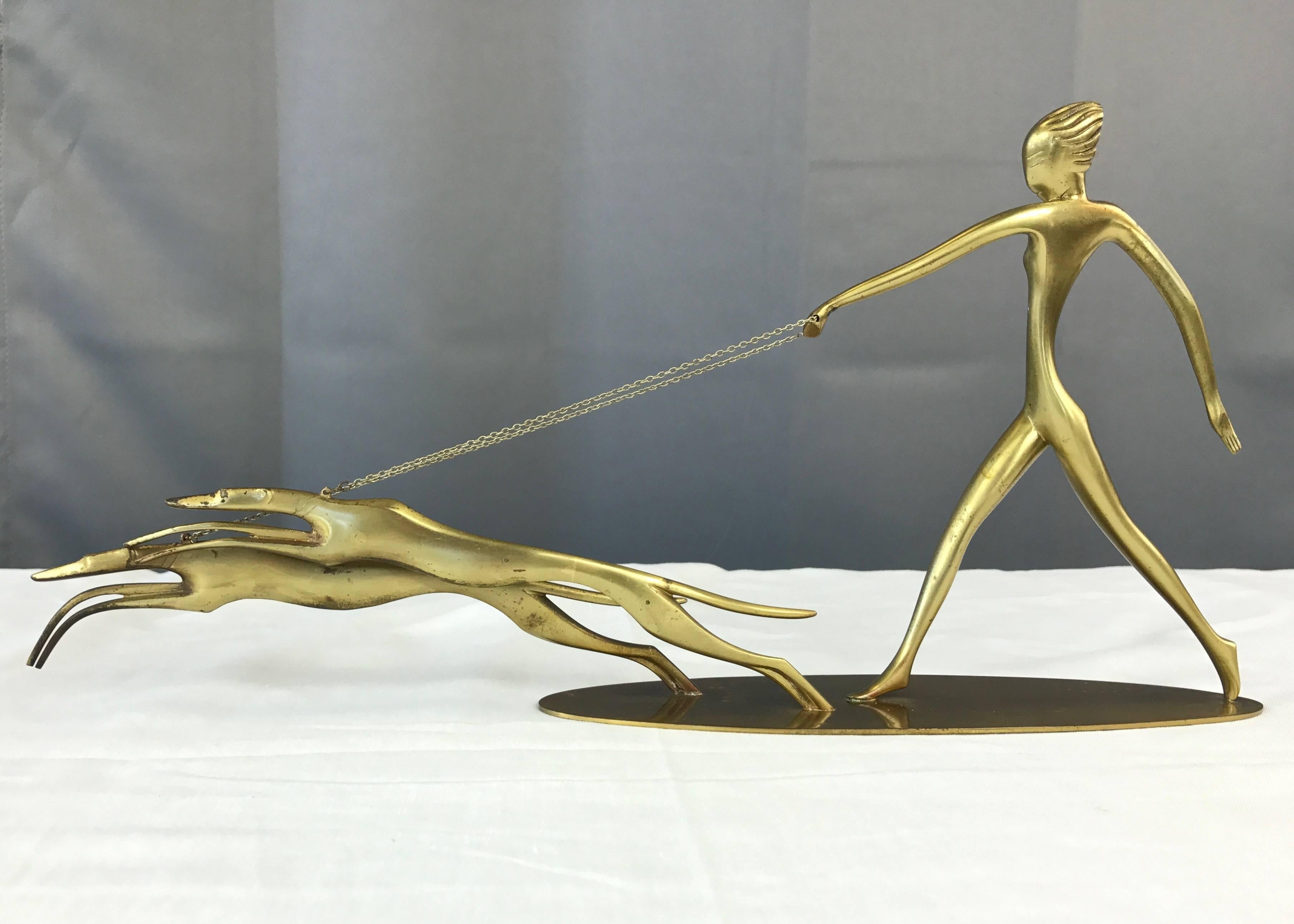 A remarkable Art Deco polished bronze sculpture titled “Diana with Dogs” by Karl Hagenauer (b. 1898–1956) for Werkstätte Hagenauer Wien.

A strong, lithe Roman goddess of the hunt strides behind a pair of equally sleek greyhounds that she holds at