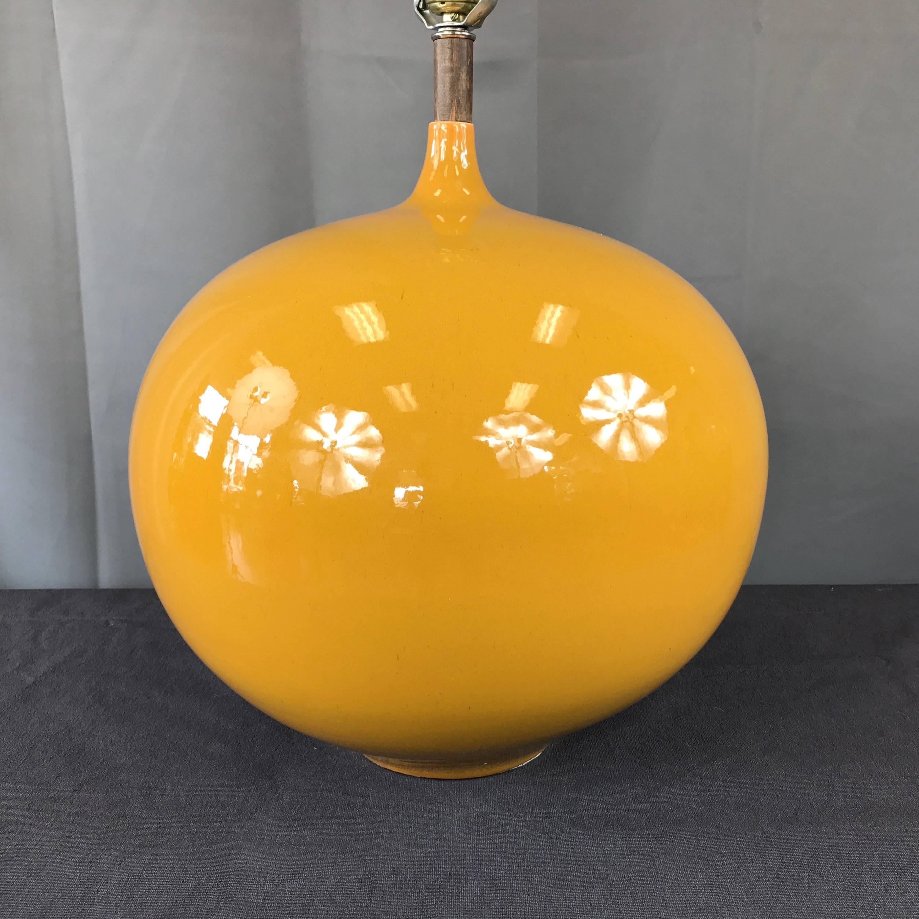 An impressively sized 1970s ceramic table lamp with orangish-yellow glaze and original shade.

Scale and color make it the sunny side up centerpiece of any room. Body shape is a classic combination of globe and onion, giving it a versatile