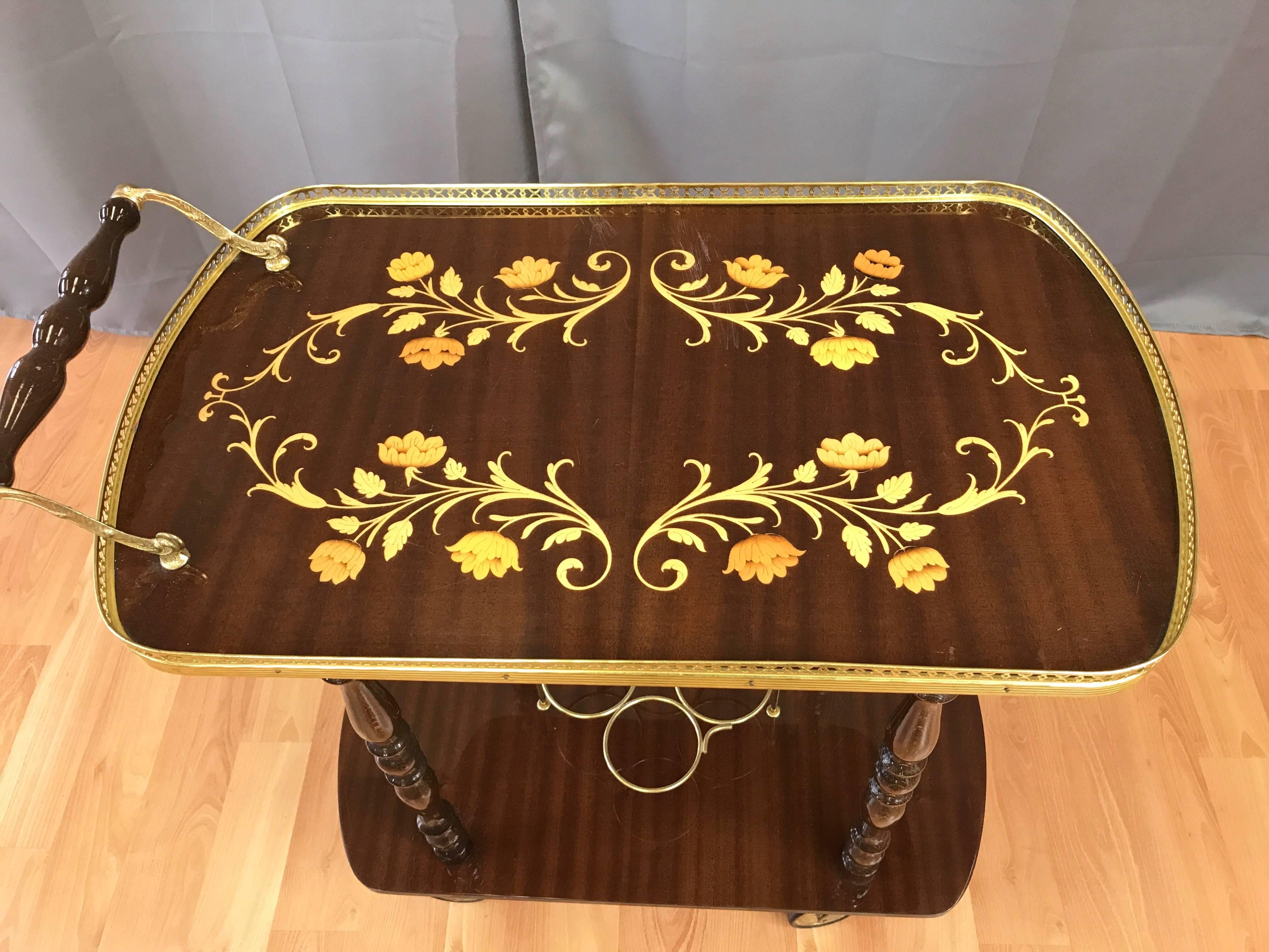 An elegant Mid-Century Italian serving or bar cart with marquetry decoration and brass-colored trim.

High gloss ribbon mahogany veneer inlaid with a beautifully rendered floral display of blond wood marquetry. Levels joined by turned wood