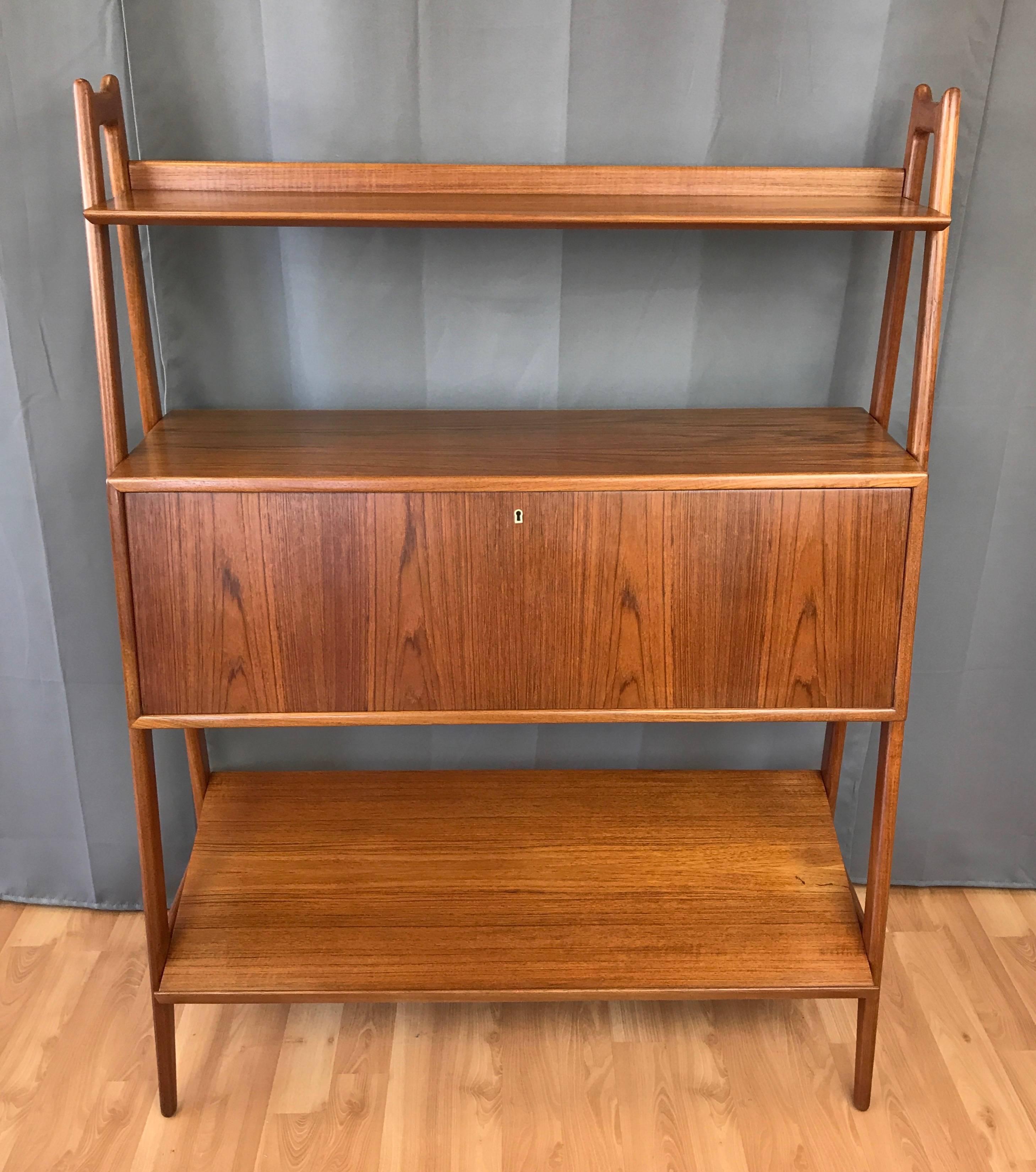 A rare freestanding teak bookshelf with floating desk cabinet by Anton Borg & Arne Vodder for Vamo Sonderborg.

Sculpted teak asymmetrical A-frame sides support a solid teak bookshelf, a floating desk cabinet, and a generously sized angled display