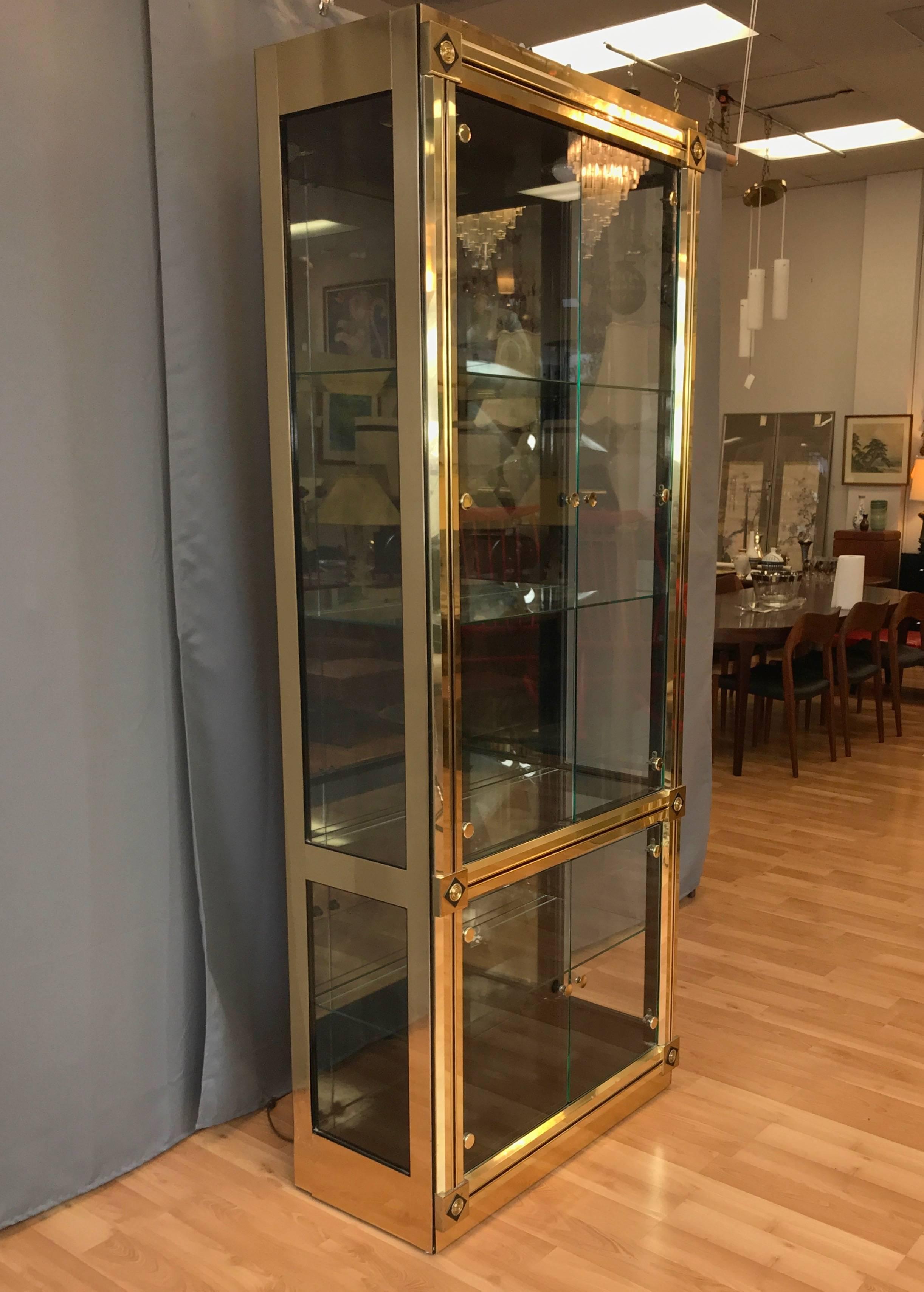 A very uncommon and impressively sized brass vitrine or display cabinet with glass doors and shelves by Mastercraft.

Regal brass-clad frame with solid brass accents and black detailing. Interior finished in semi-gloss black lacquer with a subtly