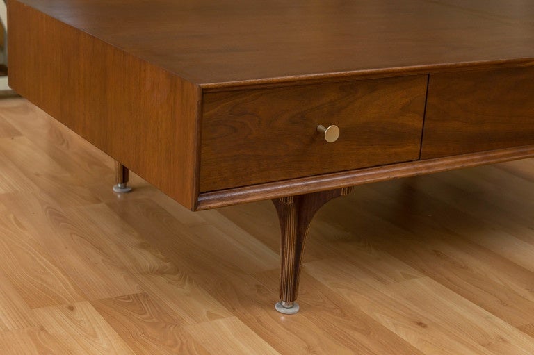 A Robert Baron designed  Walnut coffee for Glenn of California. This is a large coffee table shows a wonderful Walnut grain, has a floating drawer which can be opened from either side with a pull on it's brass knobs.  Nice detailing right down to