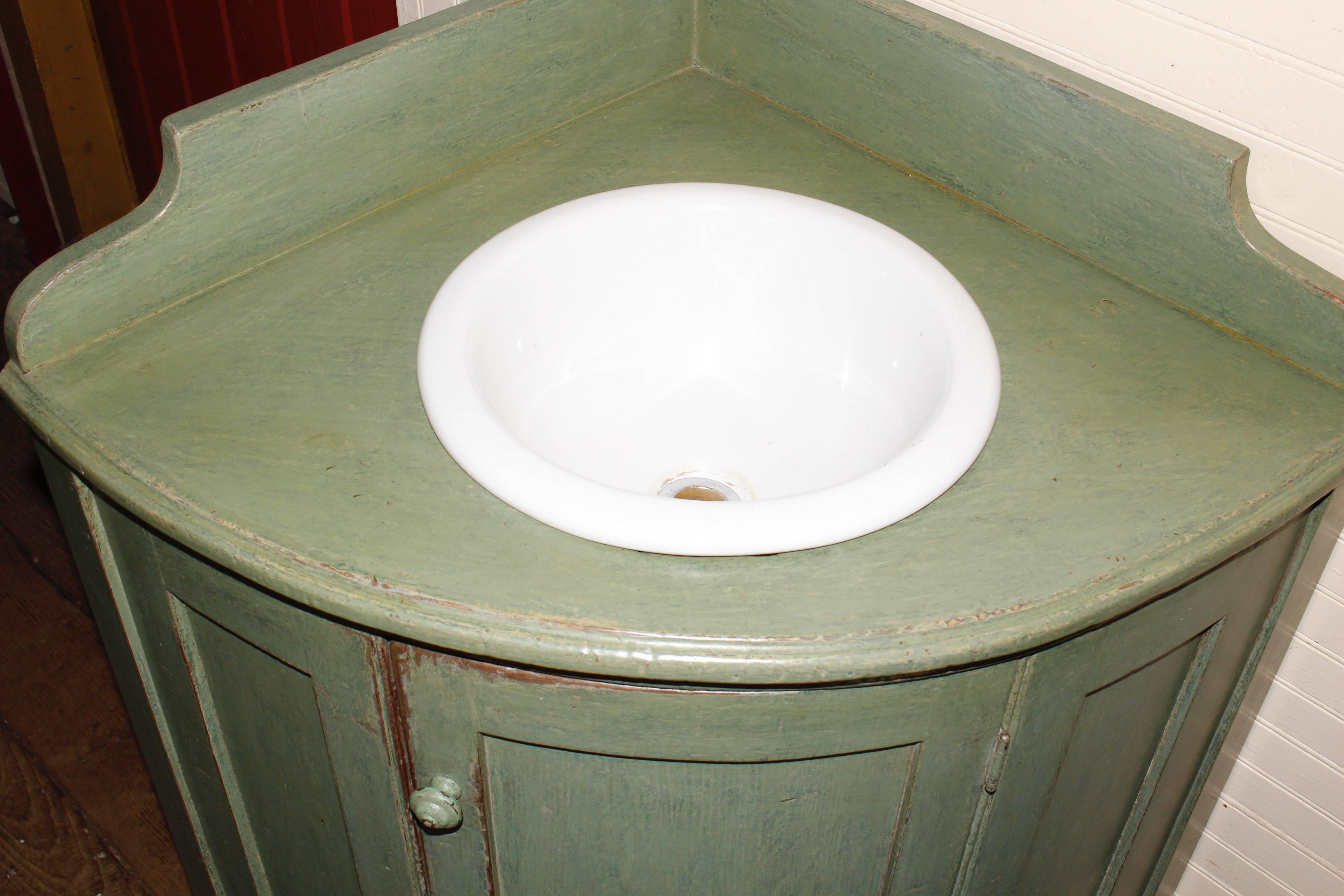 A corner vanity with a bowed front. Sink it not original to this piece.