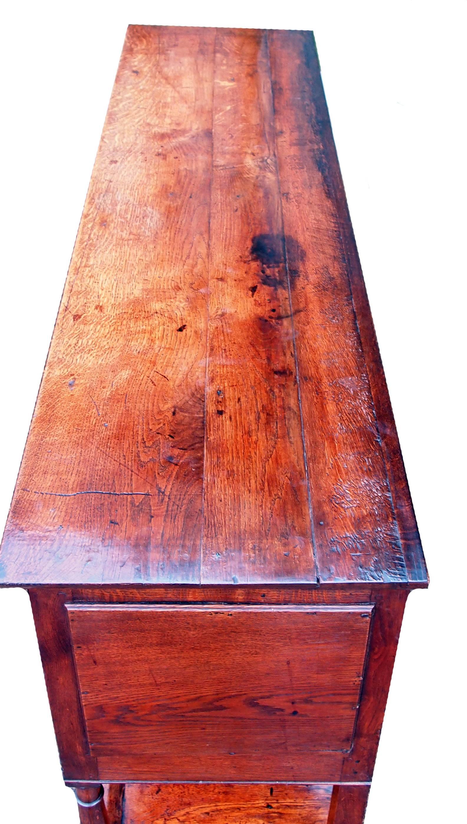 A very attractive late 18th century oak dresser base retaining good color.
Having well figured plank top above five drawers and elegant arched frieze.
With turned upright supports and original potboard below.