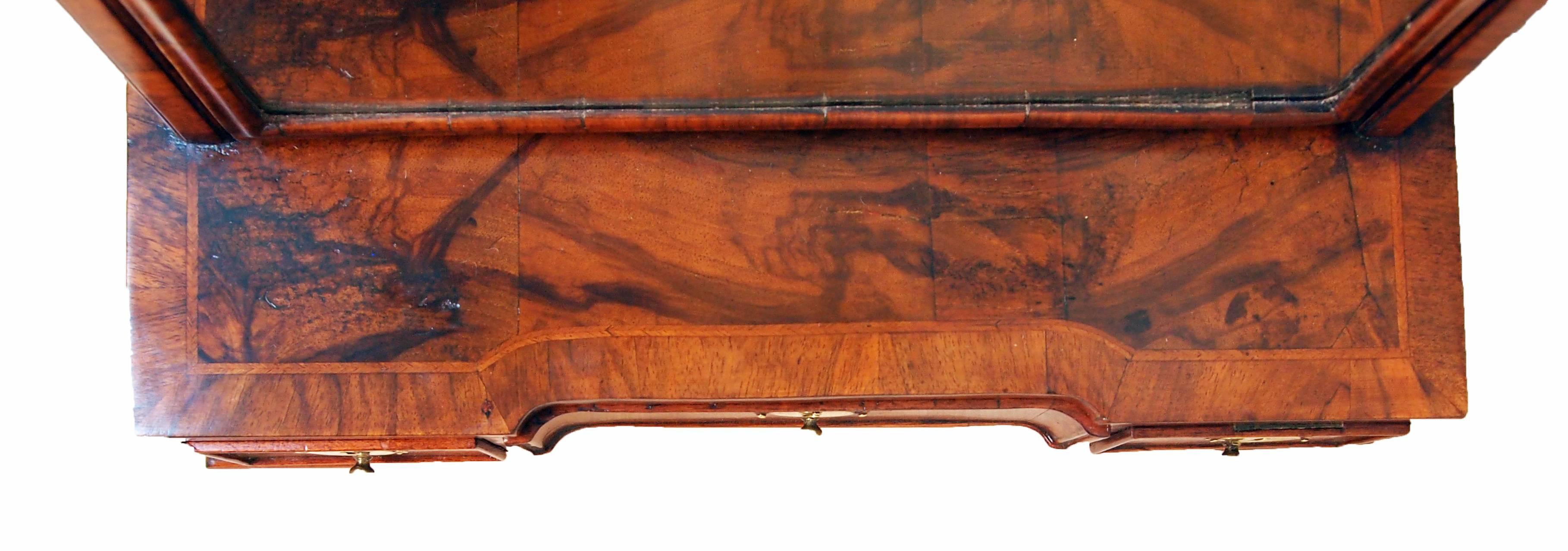 A good quality George I period walnut dressing table mirror having shaped and moulded
frame to replaced mirror plate above well figured base with three drawers raised
on replacement ogee feet.