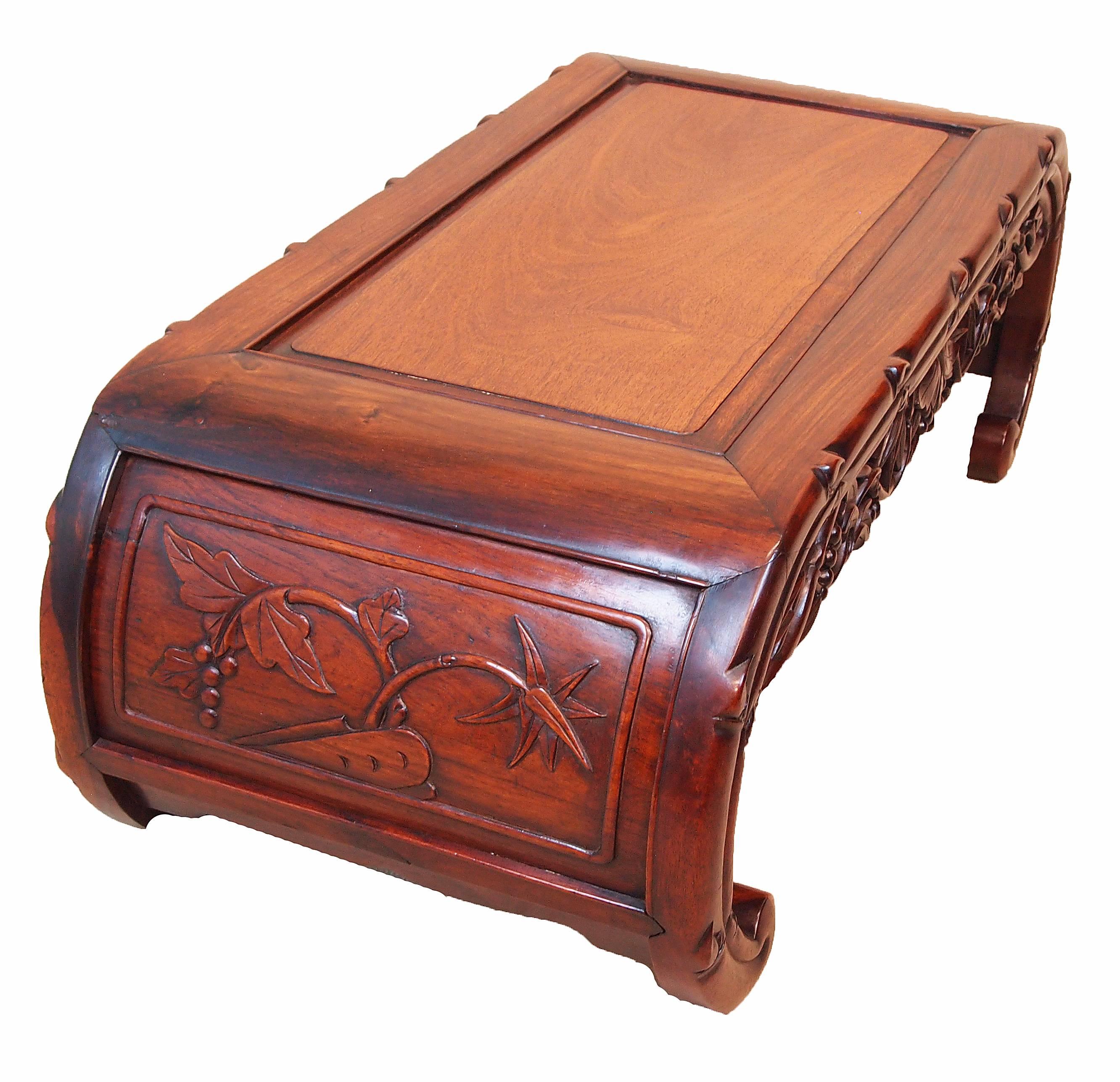 An attractive late 19th century oriental hardwood coffee, or opium, table
having well figured panelled top above pierced and carved frieze raised
on curved ends unusually with blind carved decoration.
 