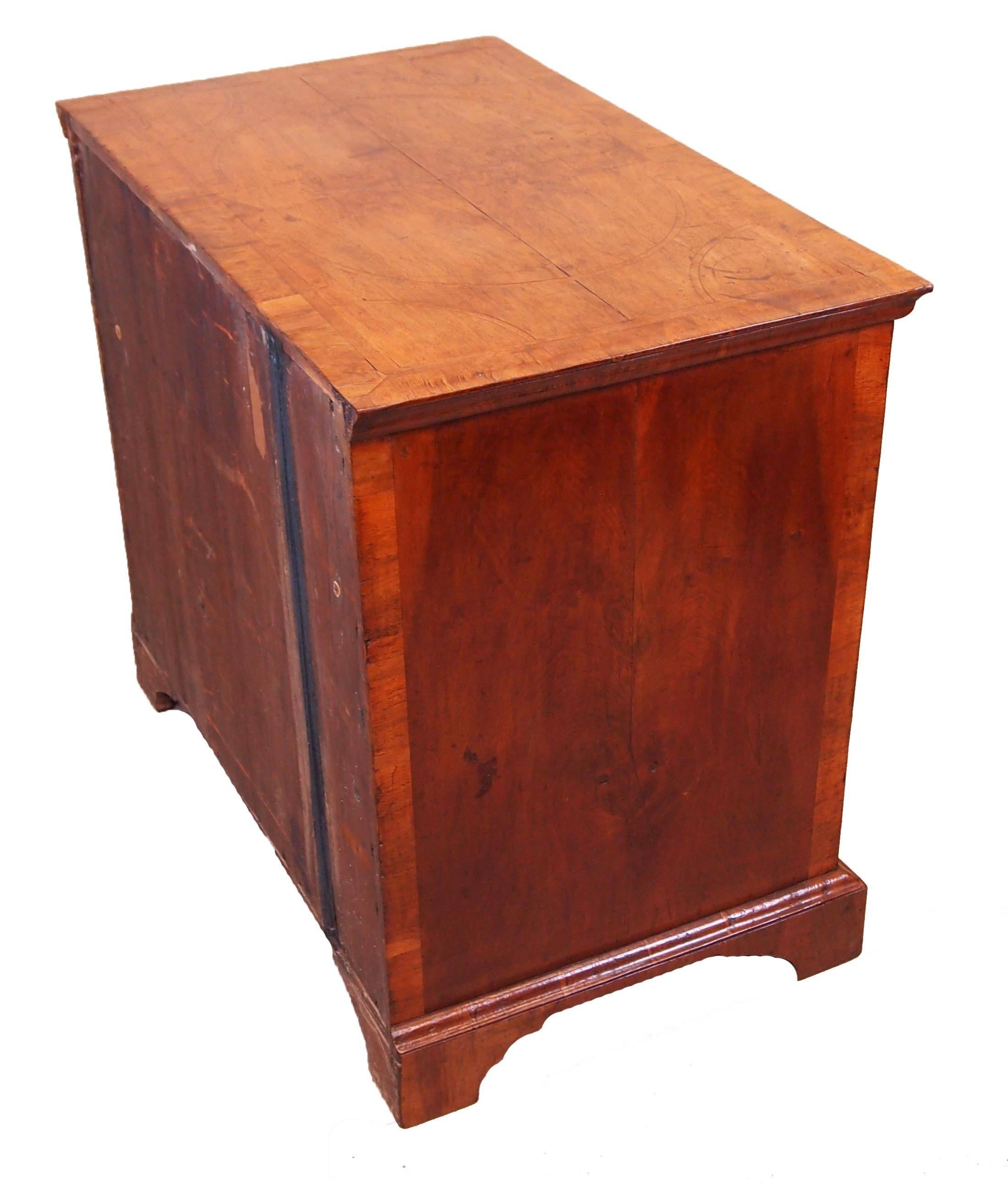 A George I period walnut chest having well figured quarter veneered top
With geometric inlaid and banded decoration above two short and three
Long drawers with replacement brasswear raised on later bracket feet.