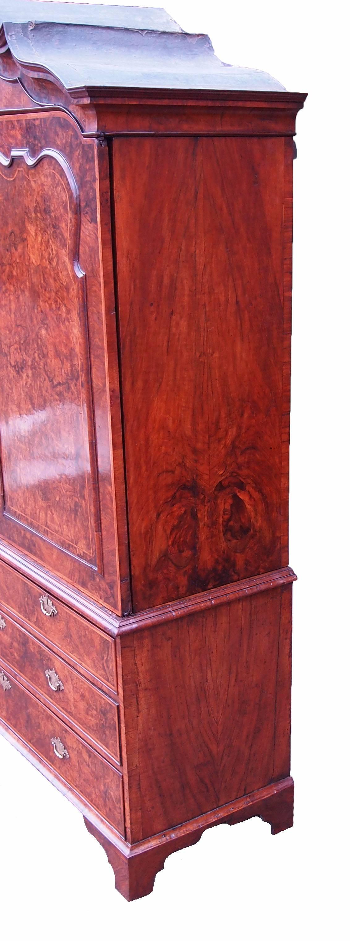 A magnificent and rare early 18th century burr walnut linen press cupboard
Having shaped canopy cornice above two superbly figured panelled doors
Above two short and two long drawers with replacement brass handles
Raised on original shaped