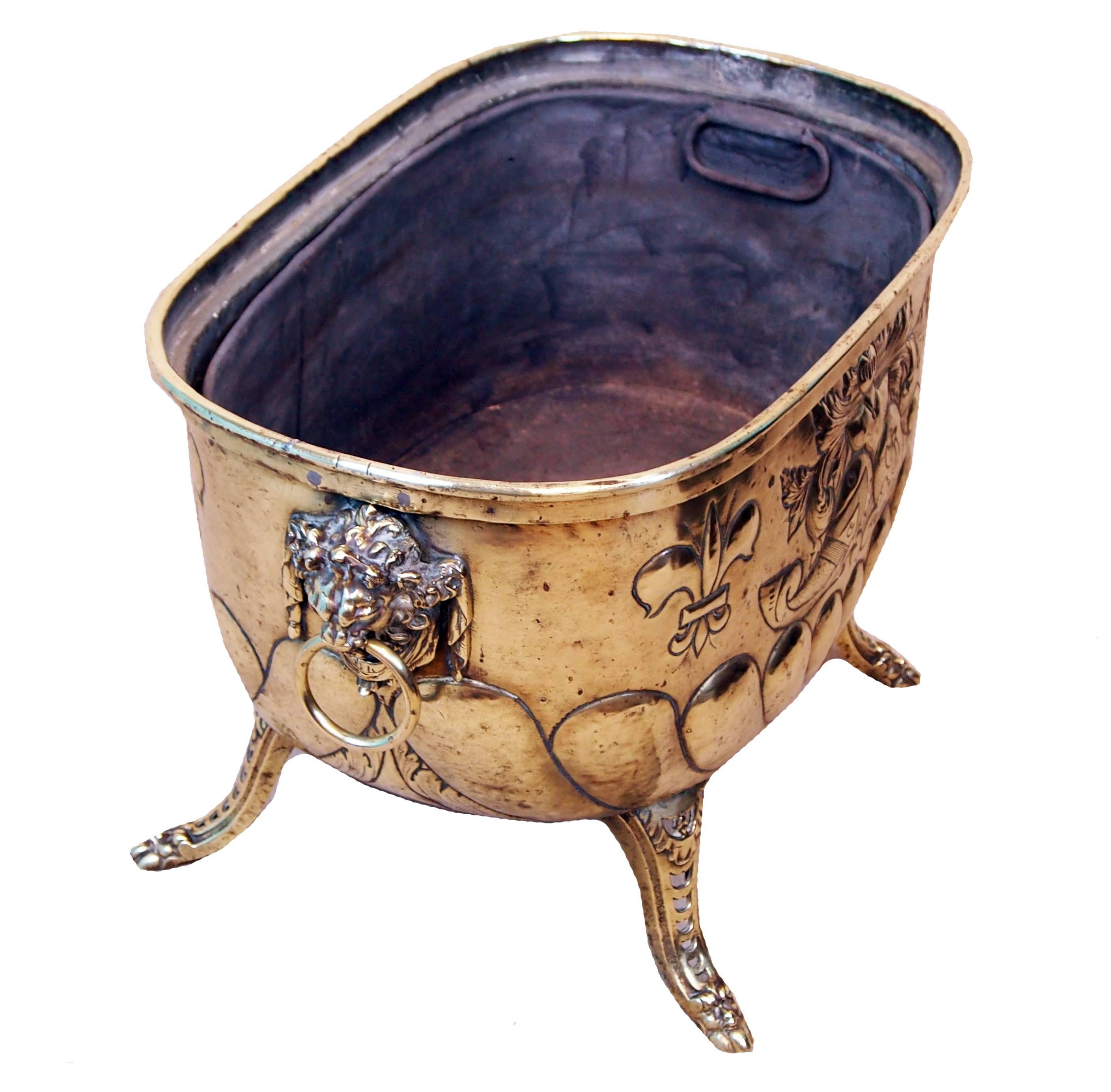 A Stunning Quality Mid 19th Century Brass Log Bin, Or
Planter, Having Armorial Typre Decoration And Original 
Lions Mask Carrying Handles Raised On Elegant
Pierced Tapering Legs