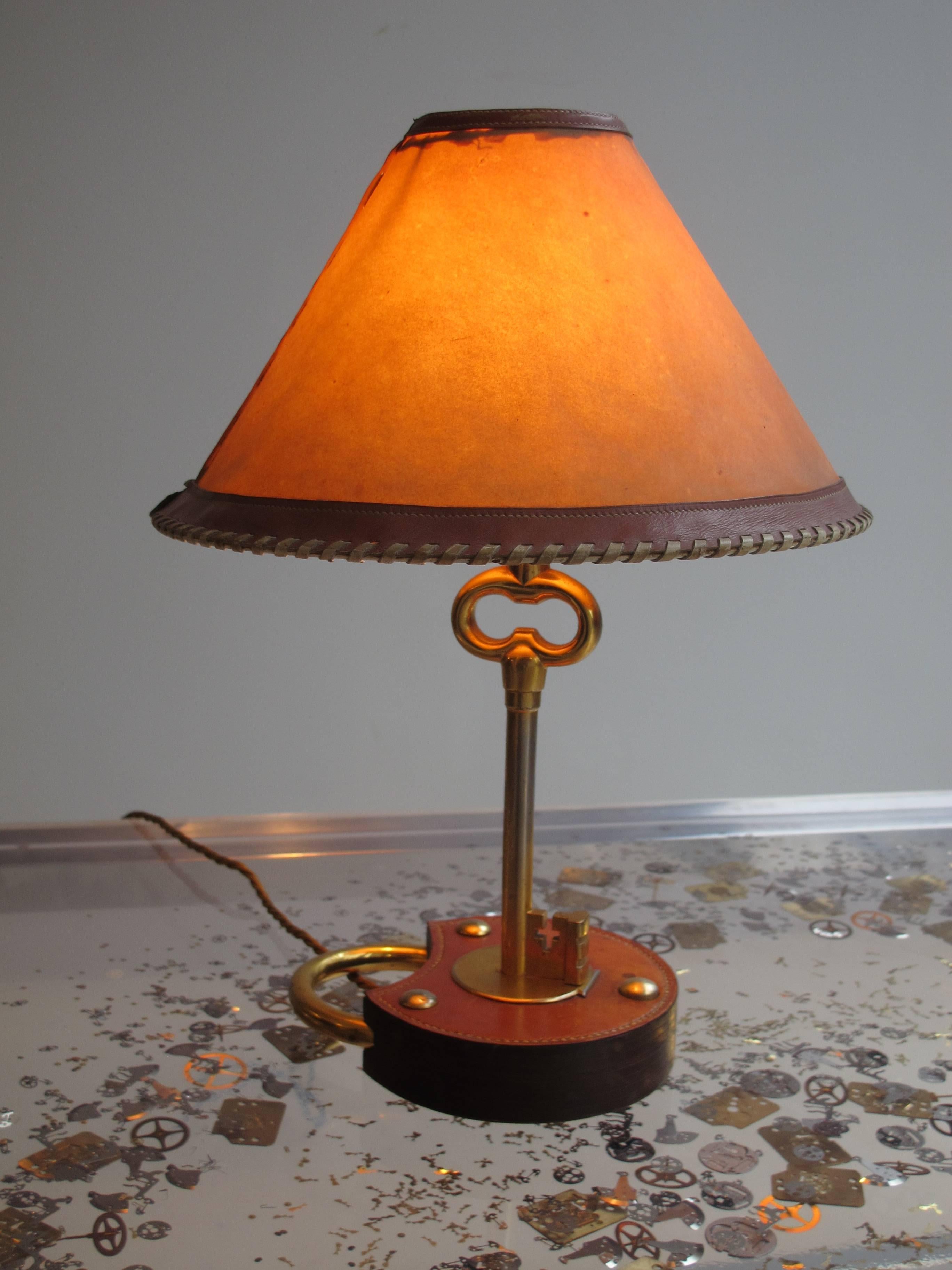 Rare lock and key table lamp, gilt metal, stitched leather and parchment by Hermes 

The shade is in parchment and leather band, there is a 2 cm rip on the shade.

On the stem of the key there is a loss of gilt showing the under the metal.

In