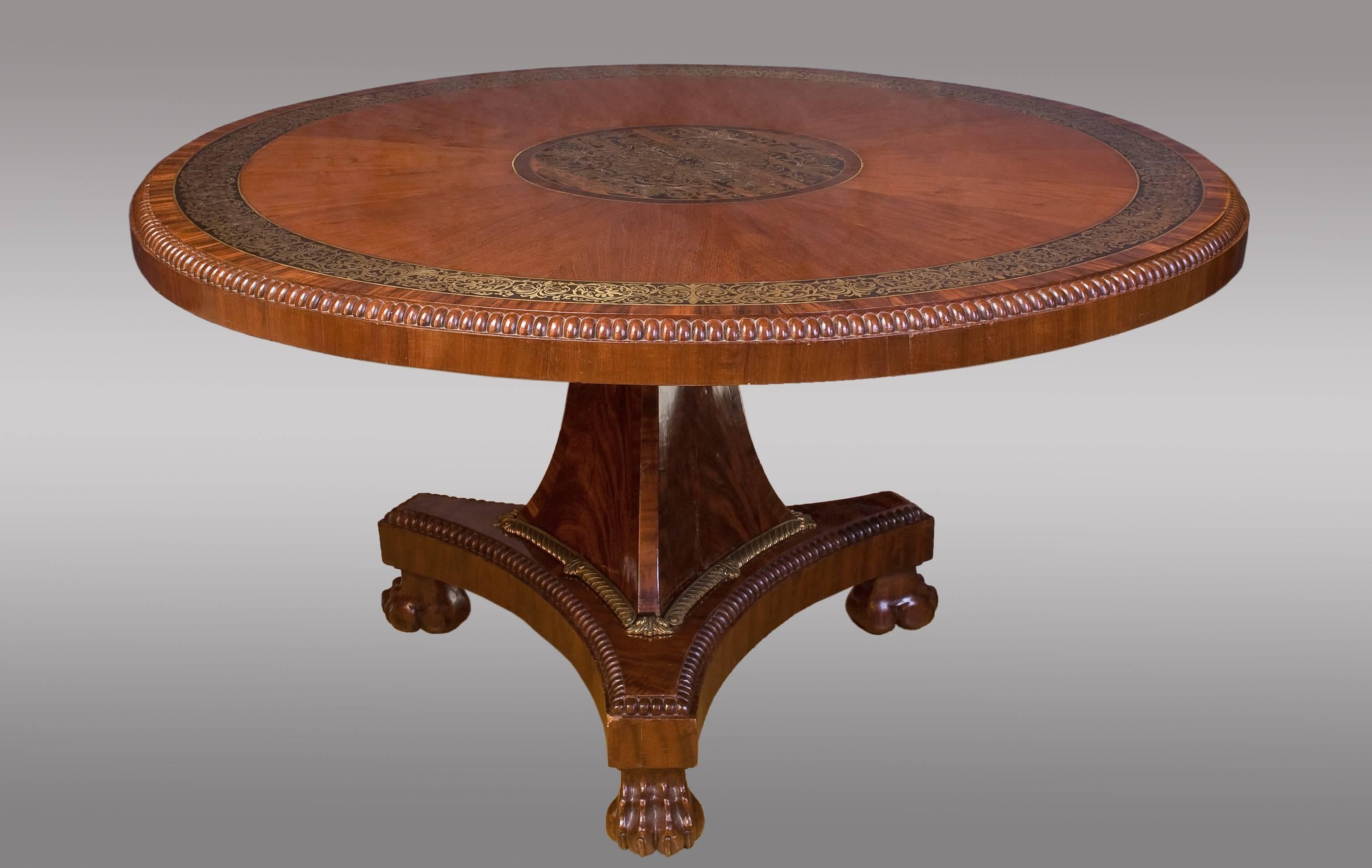 Fine early 19th century Regency period mahogahy center table.
With central arabesques inlaid brass and brass edge circular top supported by concave platform, decorated with bronze ending lions paw feet.
 