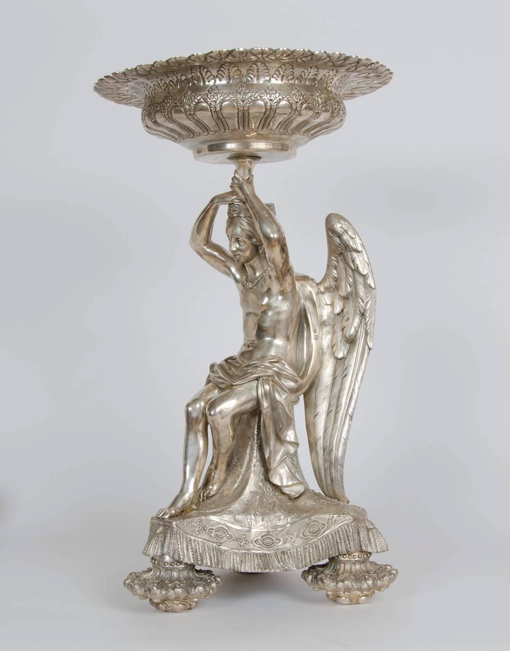 In the form of a winged angel supporting a circular tazza.