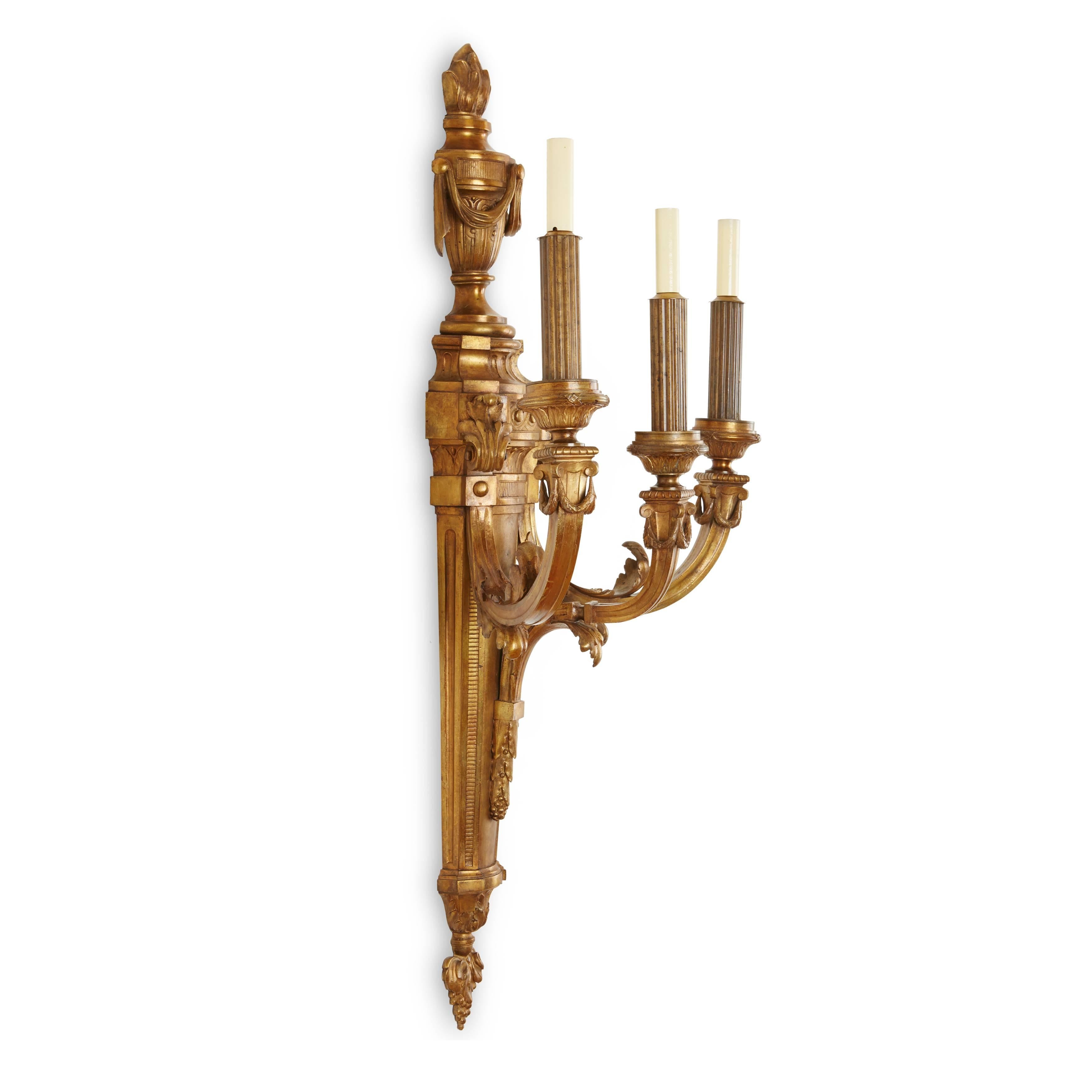 Each backplate surmounted by a flaming swagged urn on a tapering pedestal, with three acanthus-clasped scrolled branches with reeded columns.