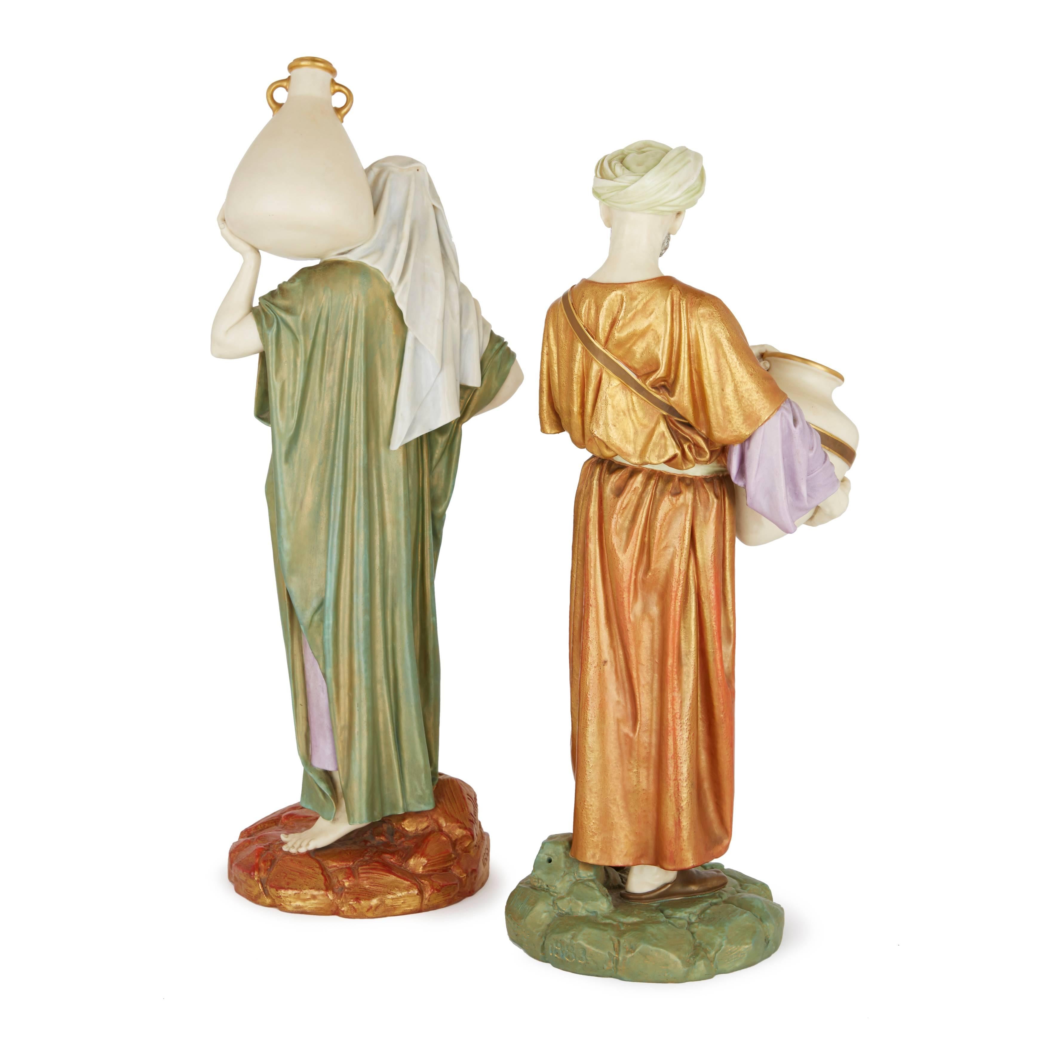 Ces deux figures orientalistes raffinées représentent un homme et une femme en costume oriental, tenant chacun une cruche d'eau en céramique. La paire a été modelée par le céramiste britannique James Hadley, qui était le principal modeleur de la
