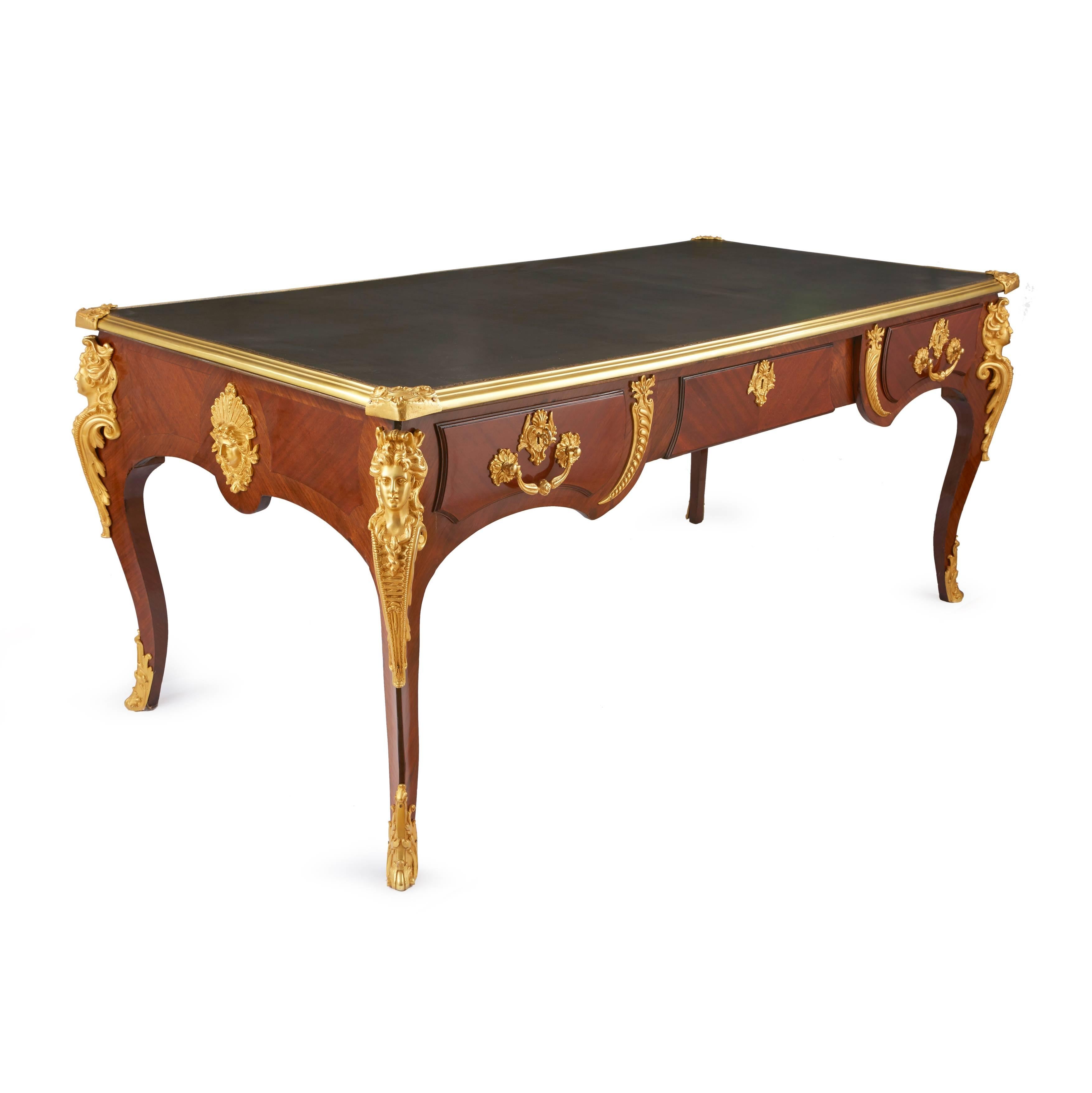 Of classical rectangular form, the four cabriole legs capped by ormolu female masks, with a further two masks to the sides, with three drawers and a leather writing surface 