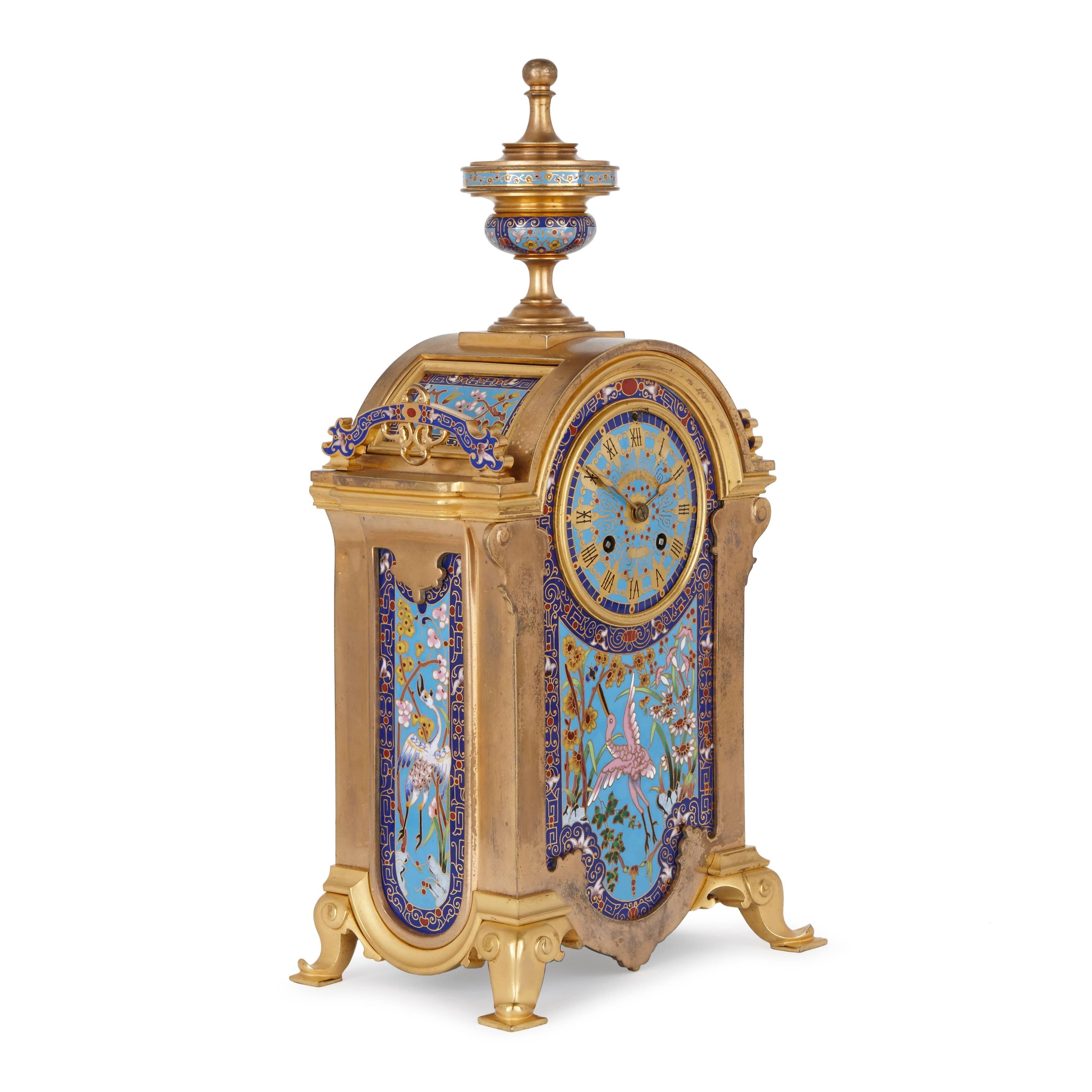 Comprising a central clock with two flanking vases, the case with central and side panels decorated with flowers and herons, the two vases similarly decorated.

Height, width and depth as follows:
Clock: 44 x 23 x 16 cm.
Vases: 33 x 11 x 10 cm.

The