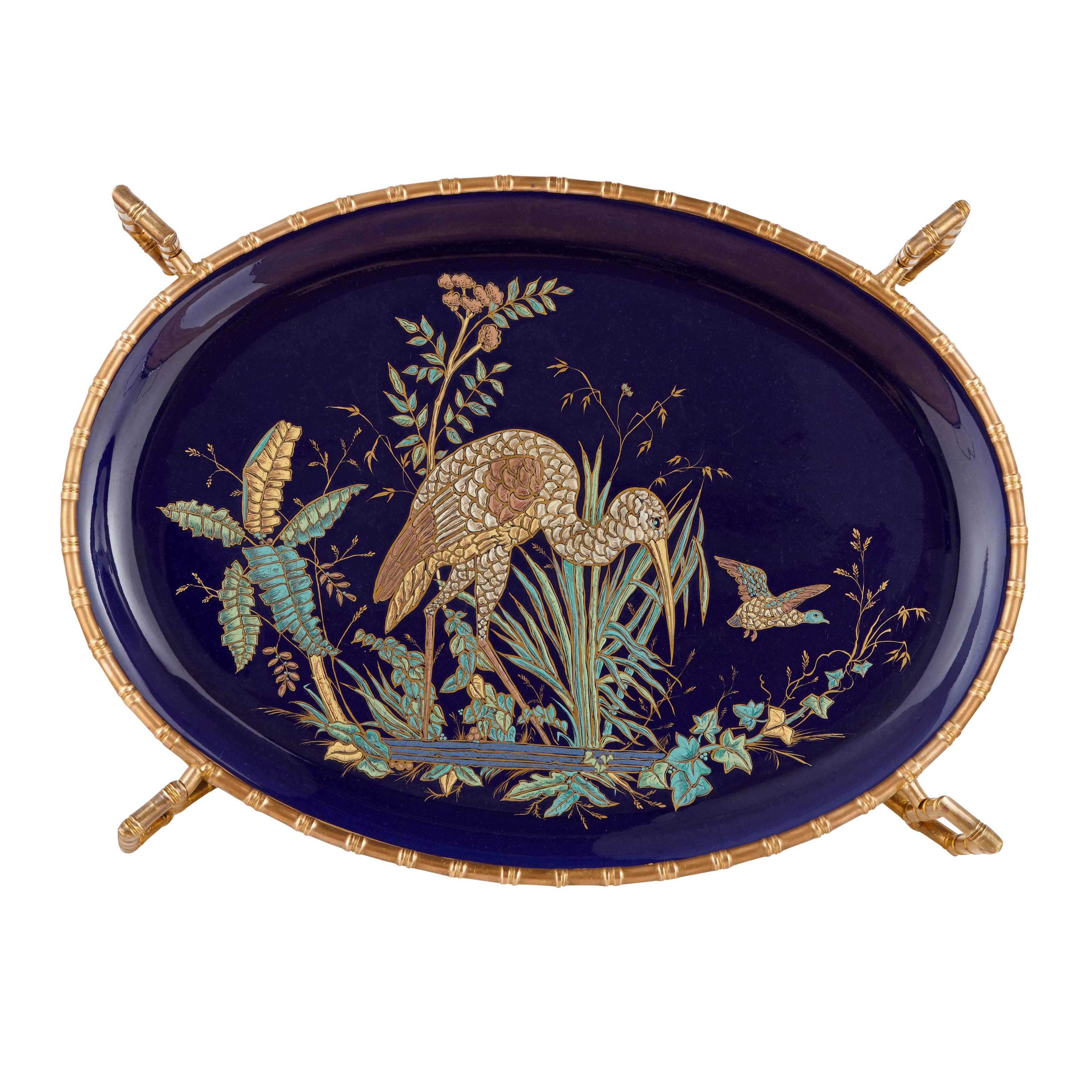 Of Chinoiserie style with an ormolu base cast to imitate bamboo wood, the tabletop depicting a large heron among flowers in lake.