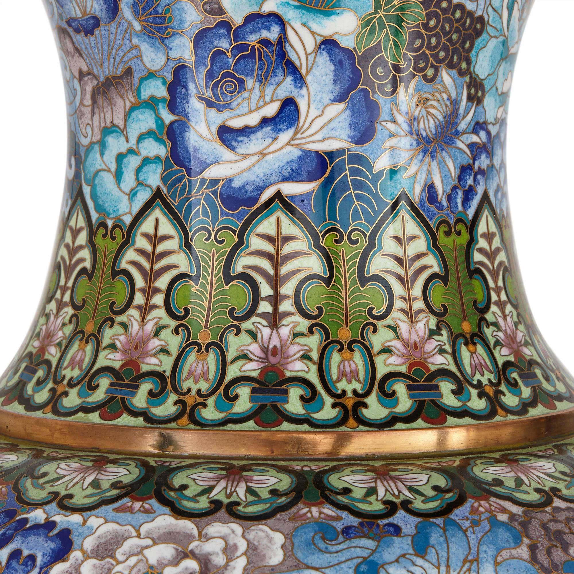 Each extensively decorated with a pattern of floral design in tonal blue colours with green and cream band decorations, and complete with wooden stands

These magnificent vases are richly decorated to an exceptionally high standard, embodying the