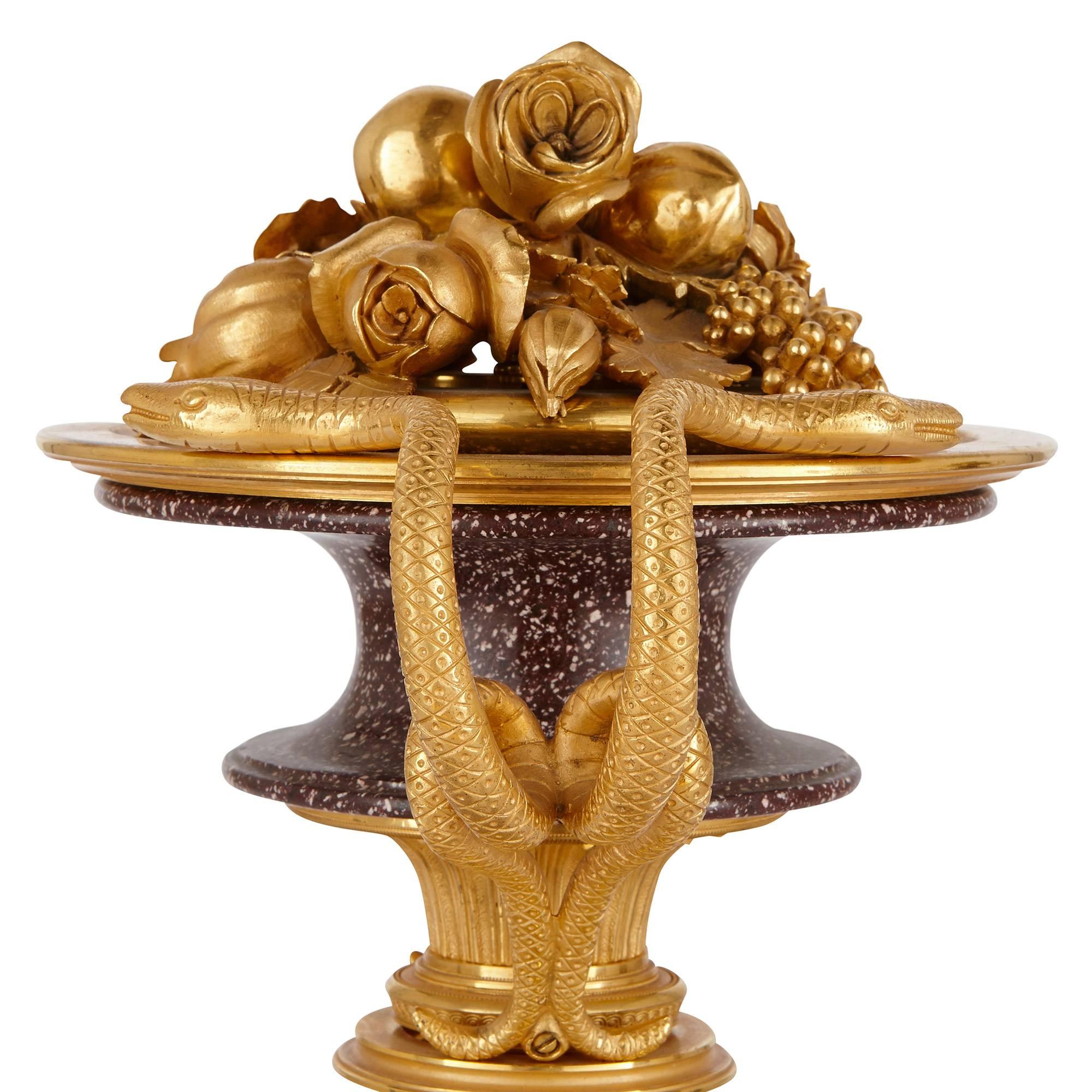 I vasi centrali in porfido dalla forma concava e arrotondata sono ornati da decorazioni di fiori e frutta in ormolu e sono affiancati da manici gemelli a forma di serpente in ormolu, tutti sostenuti da basi quadrate in porfido e ormolu.

Queste