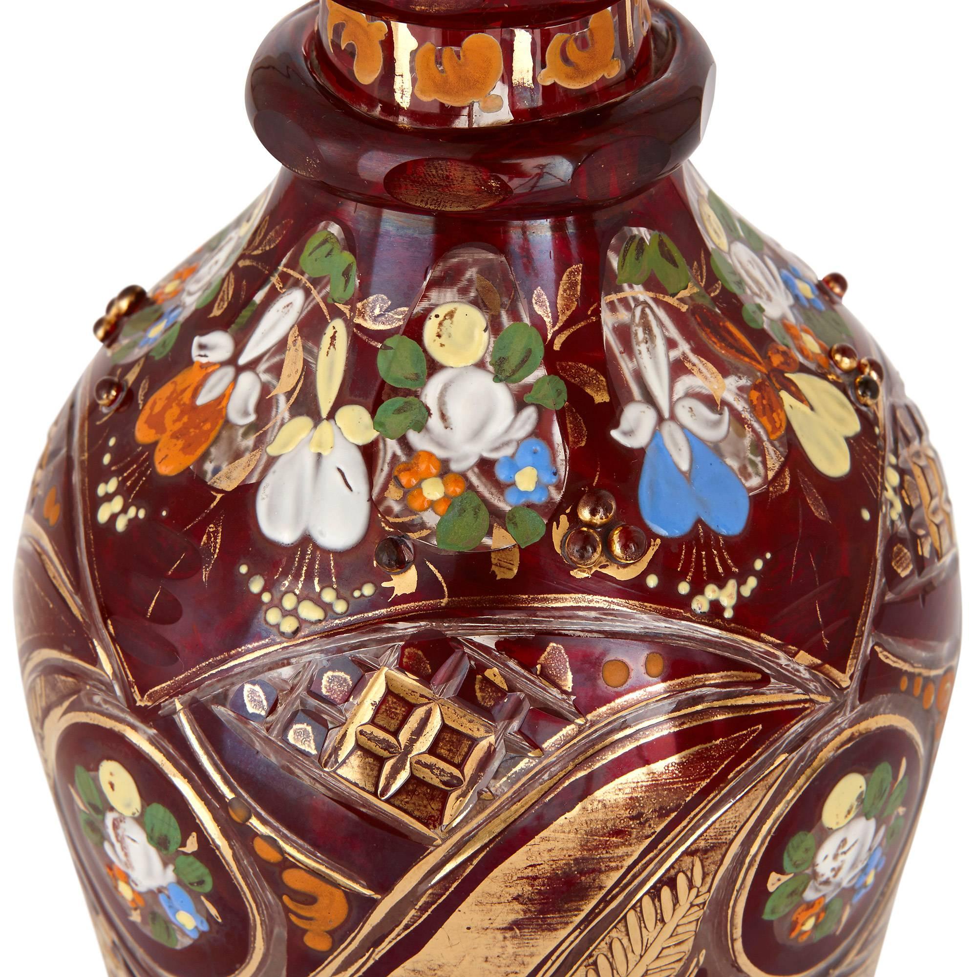 The decanter with octagonal ring knoped neck and faceted body and surmounted with a conical stopper, the ruby colored glass decorated throughout with painted flower bouquets and gilt highlights.

This opulent glass decanter exemplifies Bohemian