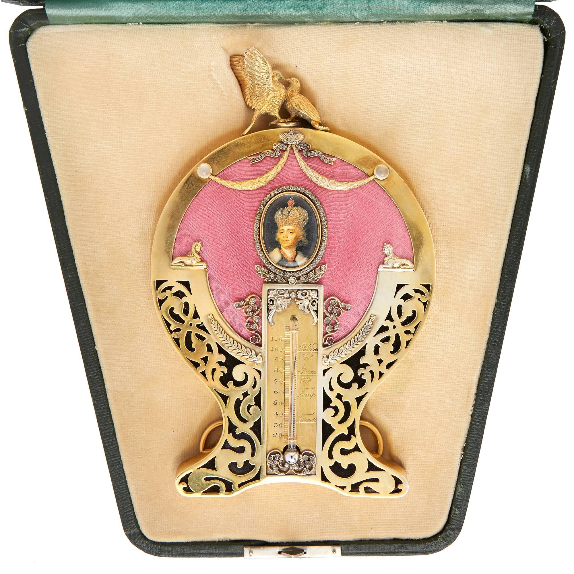 The very fine table thermometer mounted in a silver-gilt frame and set with diamonds and rubies, featuring an oval shaped photograph surrounded by a band of diamonds above the thermometer, with pink guilloché enamel decoration and silver-gilt