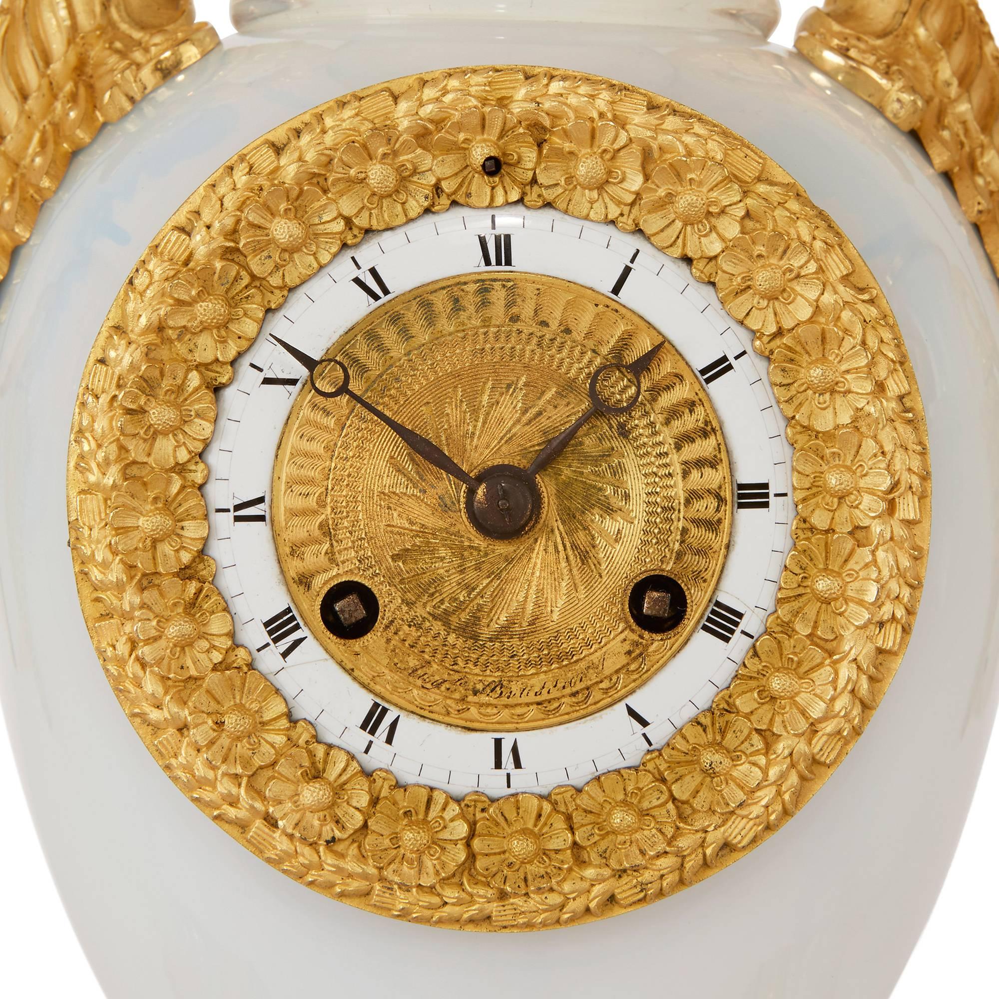 From the Restauration period; comprising a central clock and a pair of flanking vases, the central vase shaped clock with circular dial signed 'AUG. de Boussiard' and twin ormolu swan-head handles, the pair of vases similarly decorated.

The