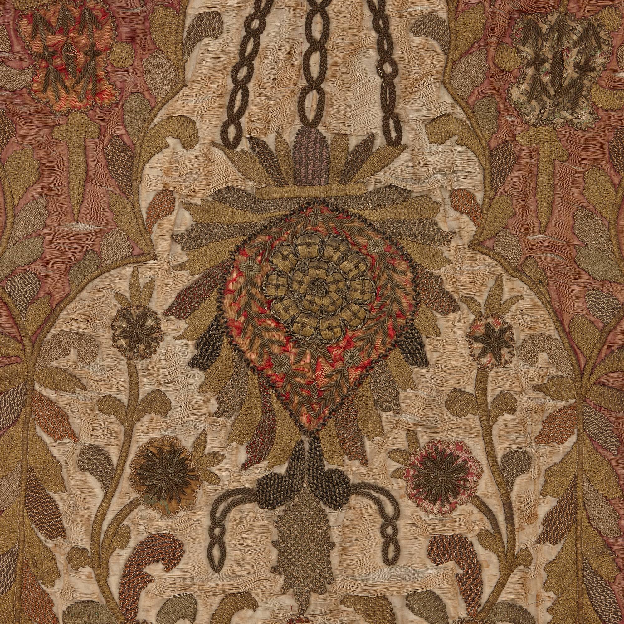 Featuring a central appliqué cream silk satin pointed motif, heavily embroidered in gilt thread floral designs, mounted with a metal rod to one end.

The intricate floral detailing of this unusual prayer rug is testament to the high quality