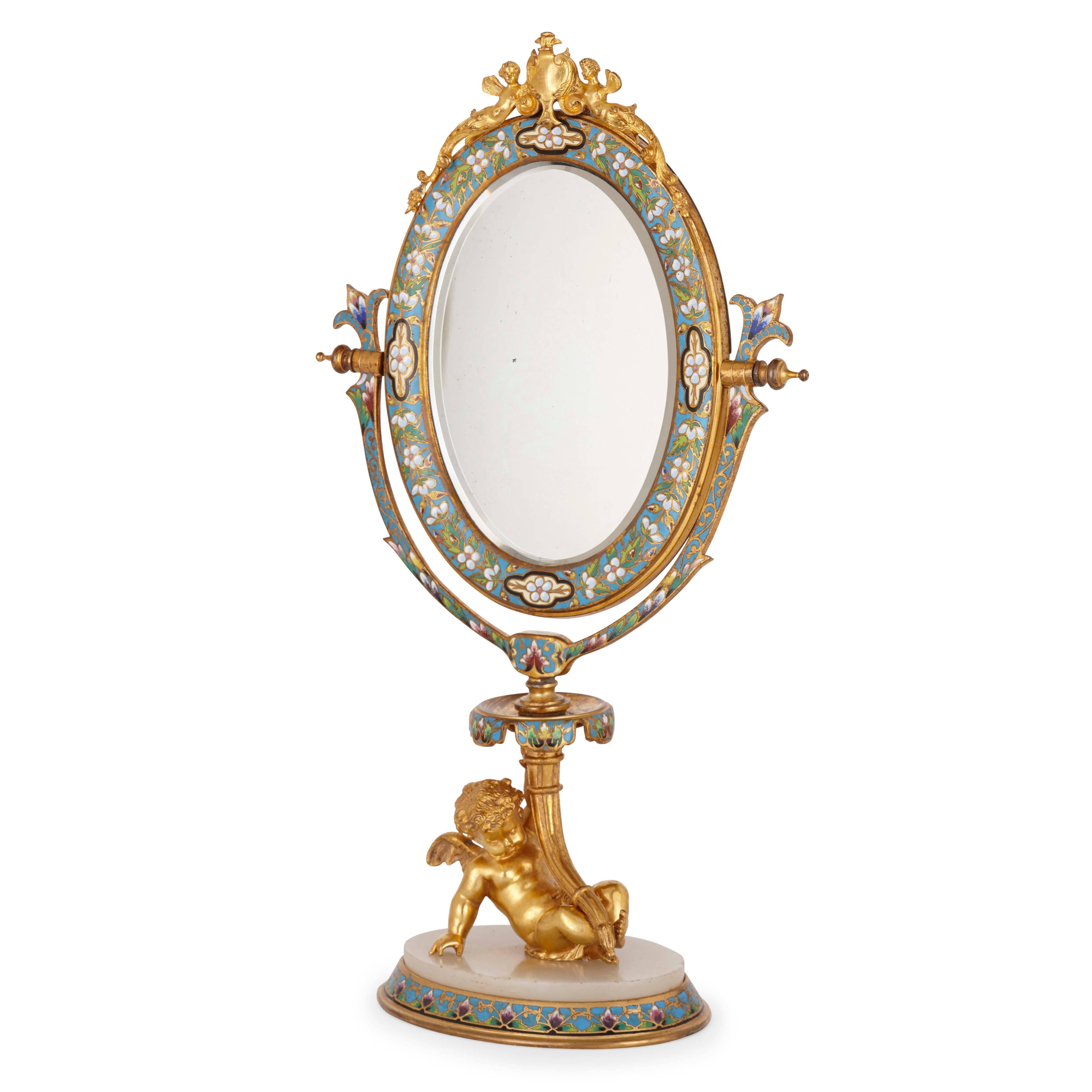 The hinged oval shaped mirror set on a cherub support with alabaster plinth, the top of the mirror surmounted by two winged female figures of ormolu.

This beautiful French mirror is decorated with a delicate, floral champlevé enamel pattern and
