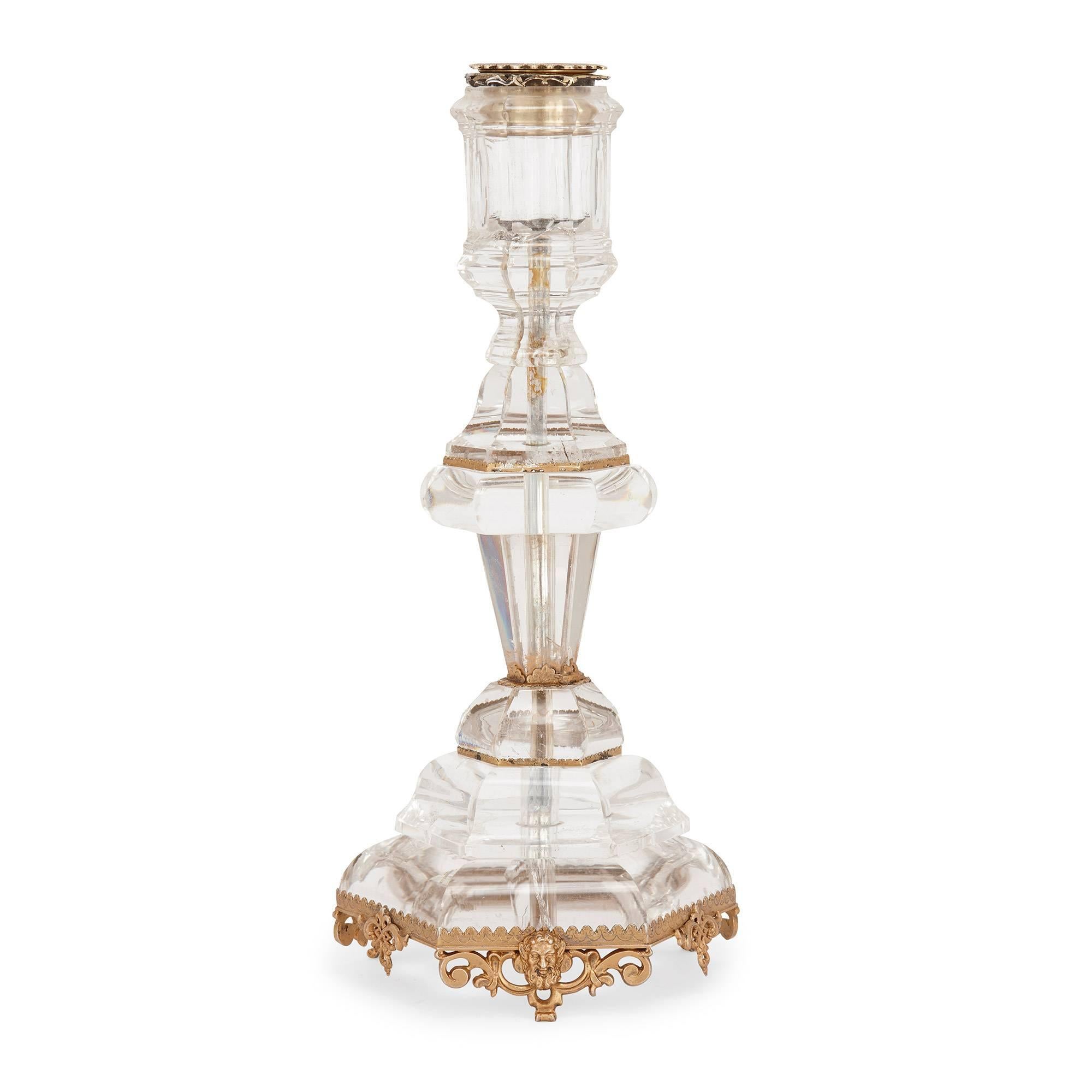 The candlestick bodies of fine, translucent rock crystal accented with silver gilt mounts; the candlestick base mounts decorated with neo-Gothic style patterns and masked faces.

The neo-Gothic style was a movement that began in England during the