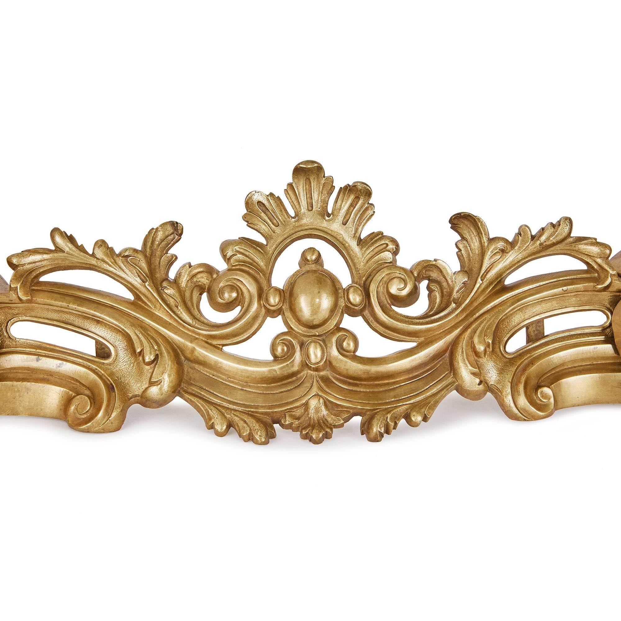 This elegant gilt bronze fireplace fender is decorated in a manner typical of the Rococo style. Featuring large, swirling foliate embellishments, the work is permeated with a sense of dynamism and movement, particularly at its C-shaped edges, and