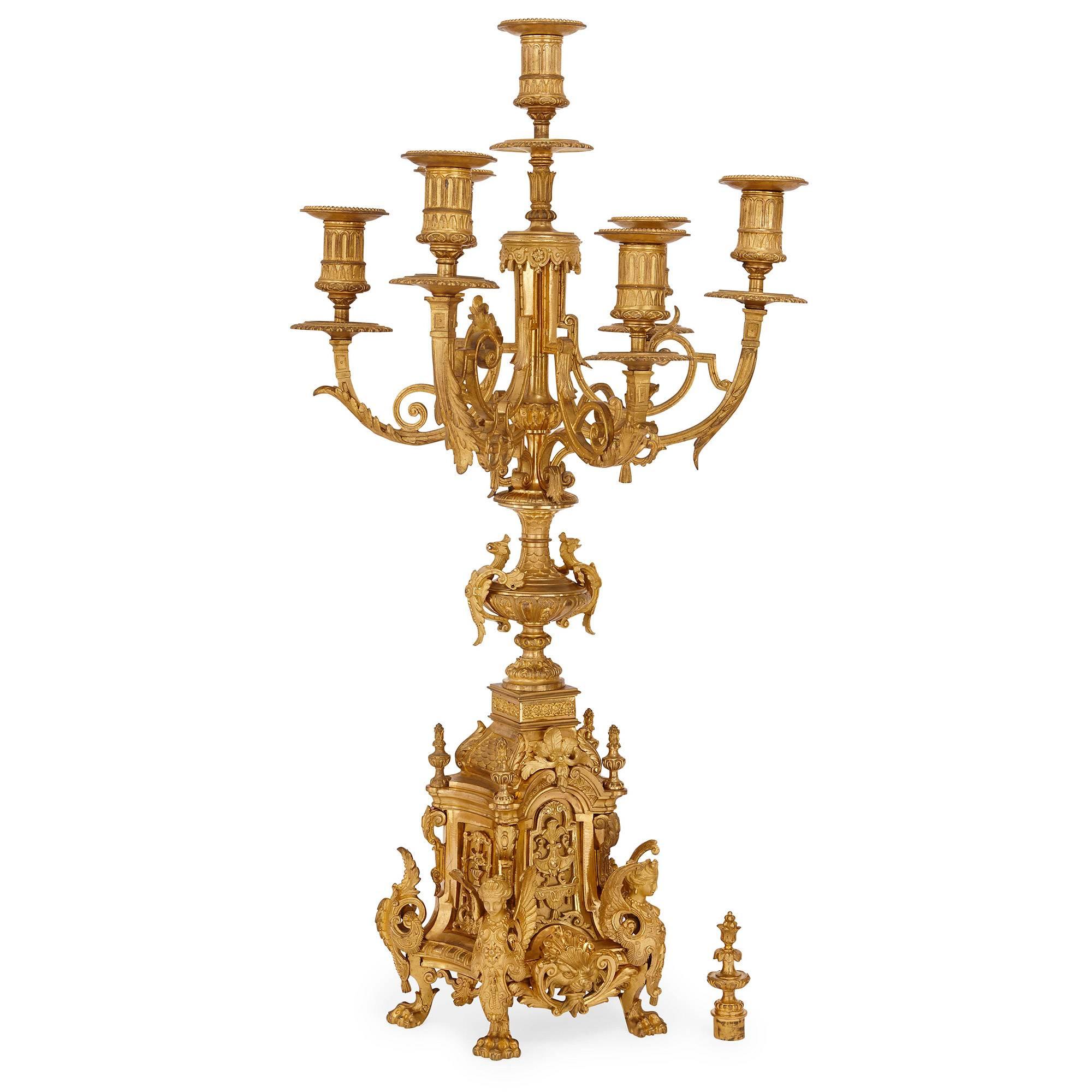 This monumental antique French clock set is composed of a central clock and a pair of flanking candelabra. The clock itself features a large central gilt bronze dial inset with enamel plaques with the Roman numerals and inscribed 'H. Jondet / 147.