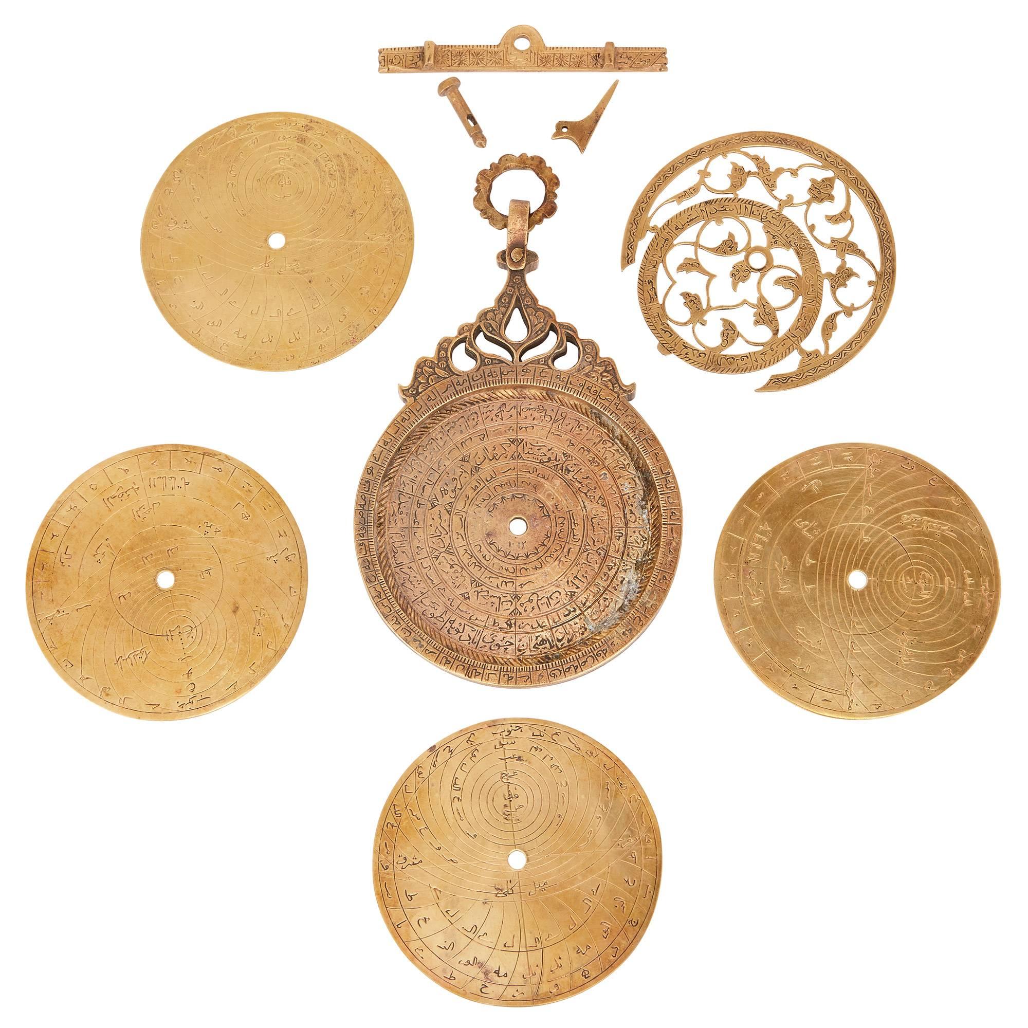 This unusual antique astrolabe is comprised of nine distinct pieces, which include the mater, the rete, four plates and three brass pieces. The mater decorated in the arabesque style, featuring with lobed palmettes and Arabic inscriptions. The