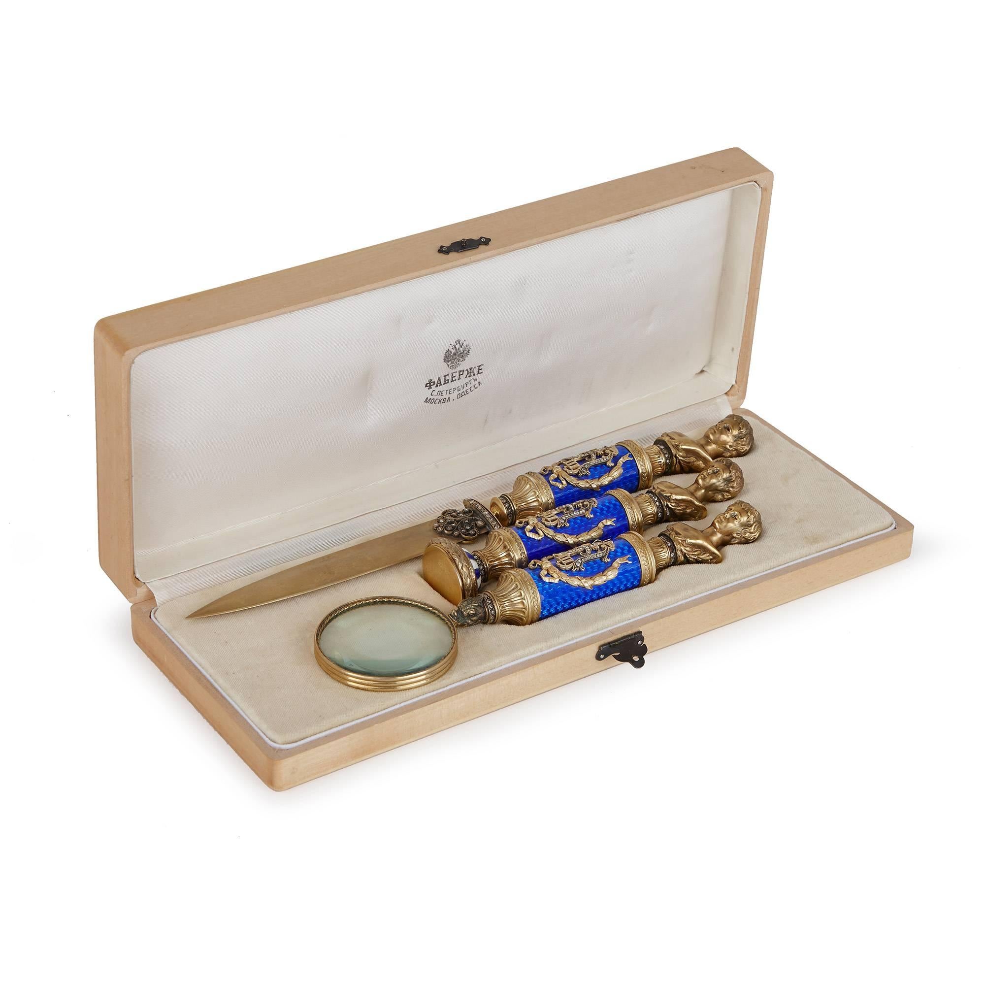This beautiful three-piece desk set has been carefully crafted in the style of Faberge. The set comprises a letter opener, a seal and a magnifying glass, all similarly decorated with diamond Emperor Alexander III monogram against a blue guilloche