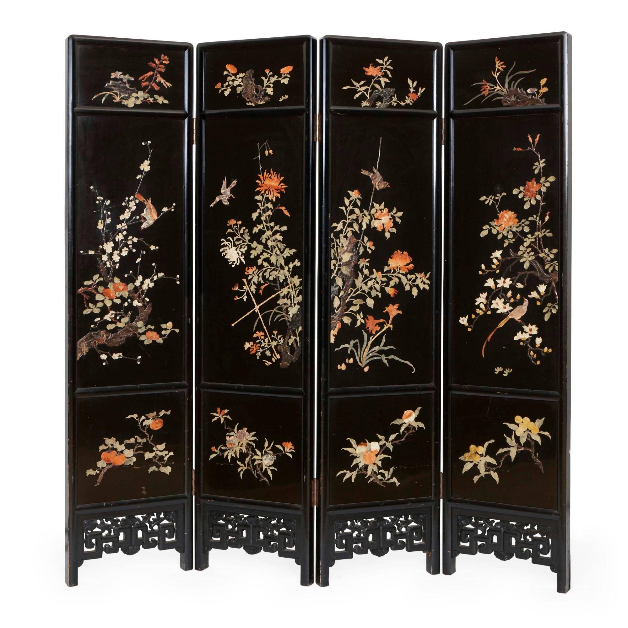 This stunning antique Chinese folding screen is of typical form, with four ebonized wood panels. On the front, each panel is delicately inlaid with soapstones in orange, green, blue and cream colors. The soapstone embellishments depict delicate