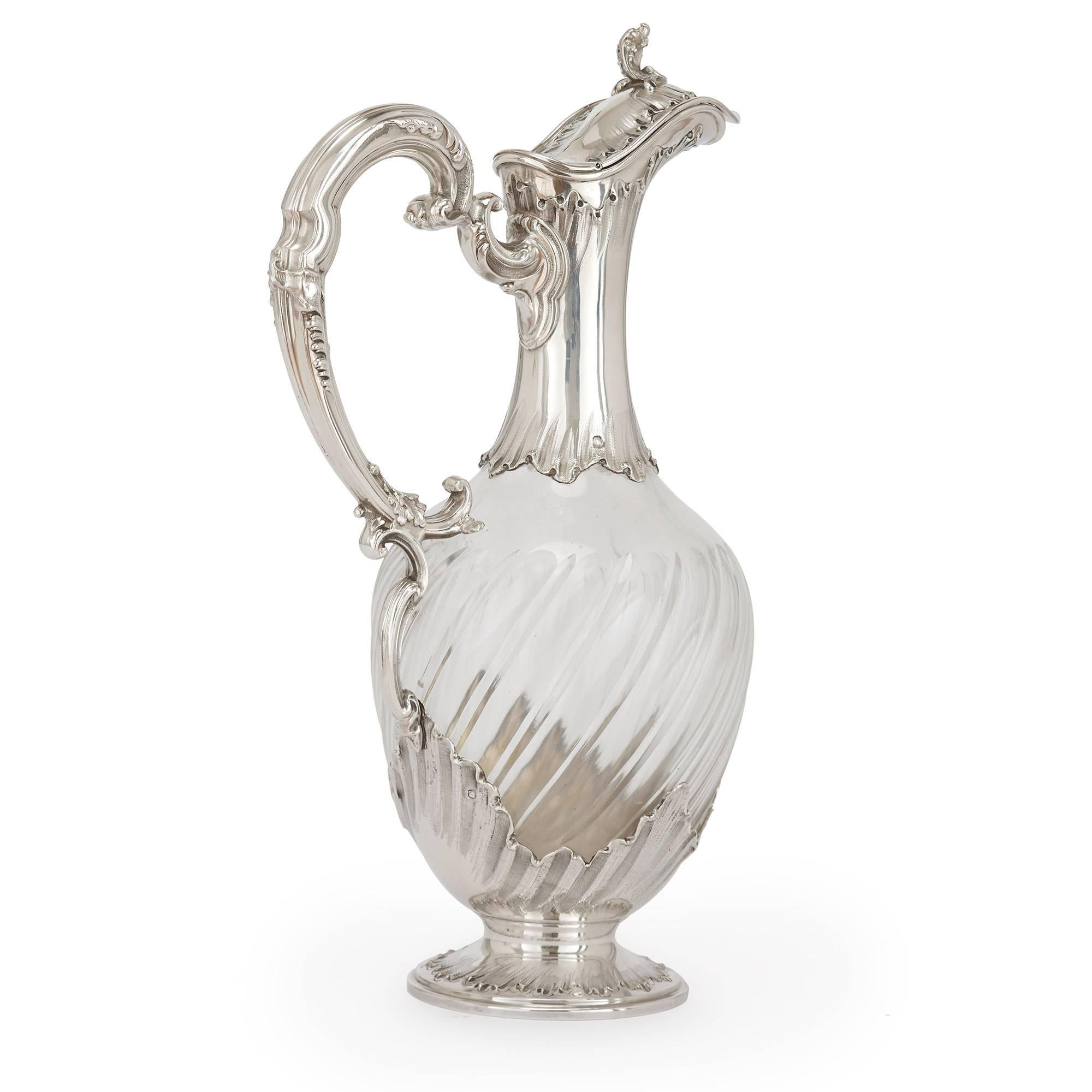 These stunning silver and crystal claret jugs are of typical form, with twisted crystal bodies featuring a fluted decoration and silver necks leading to hinged tops and scrolling handles. The pair are set on circular silver bases, with makers marks