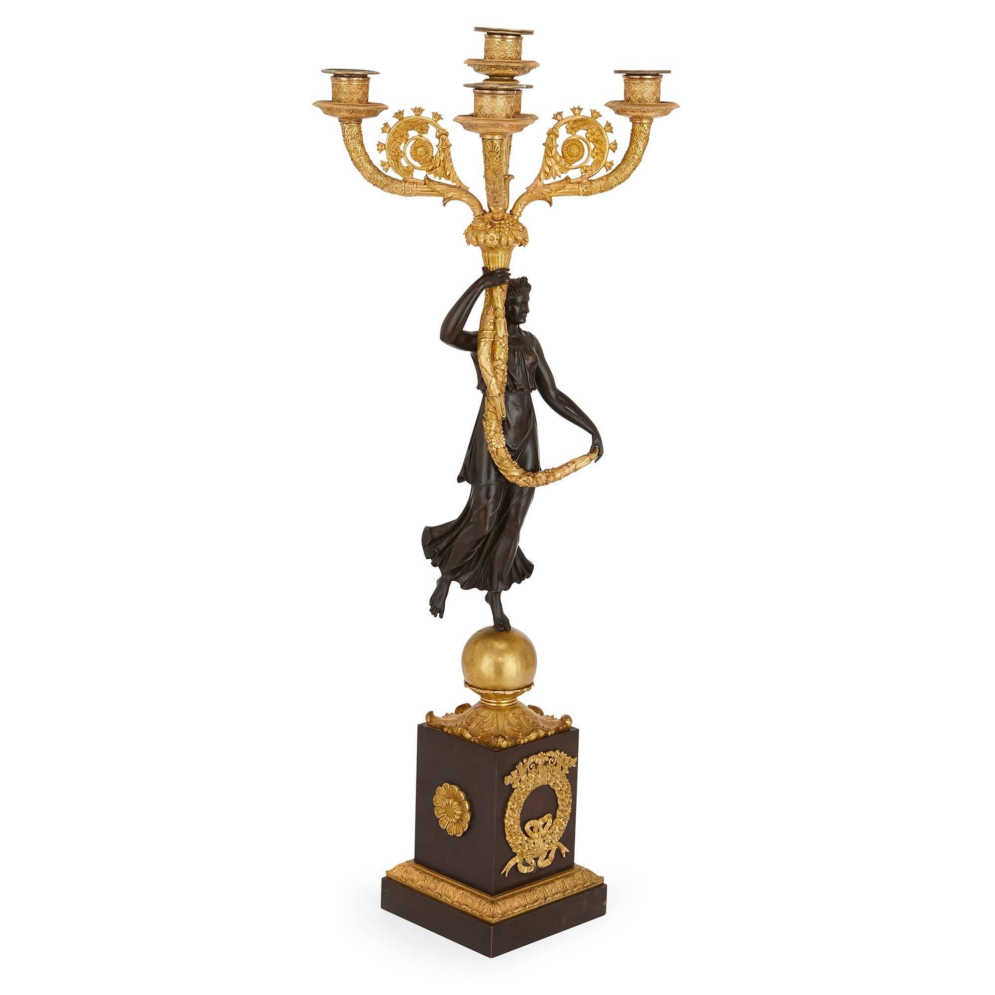 These fine and large French candelabra date from the Empire period of the 19th century and beautifully contrast the different finishes of gilt and patinated bronze. Each piece is modeled as a full length female figure holding aloft a five light