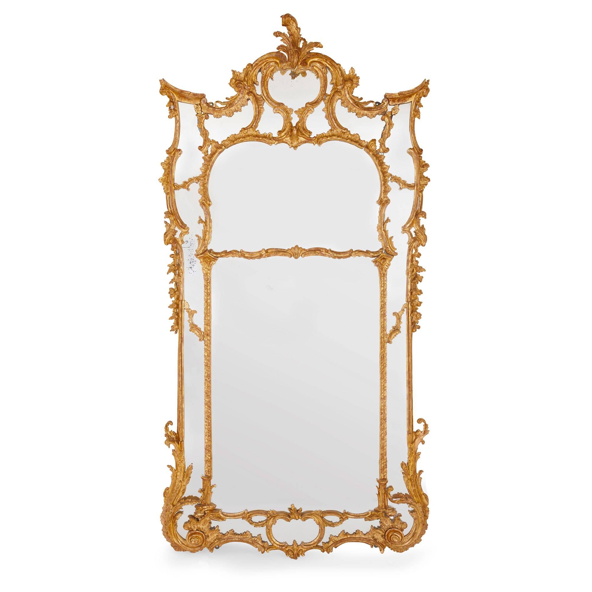 These monumental 19th century English giltwood mirrors are stunning in their ornate Rococo style design. Each mirror contains two larger mirror panels bordered by a large number of smaller mirror panels, each individually framed in carved giltwood.