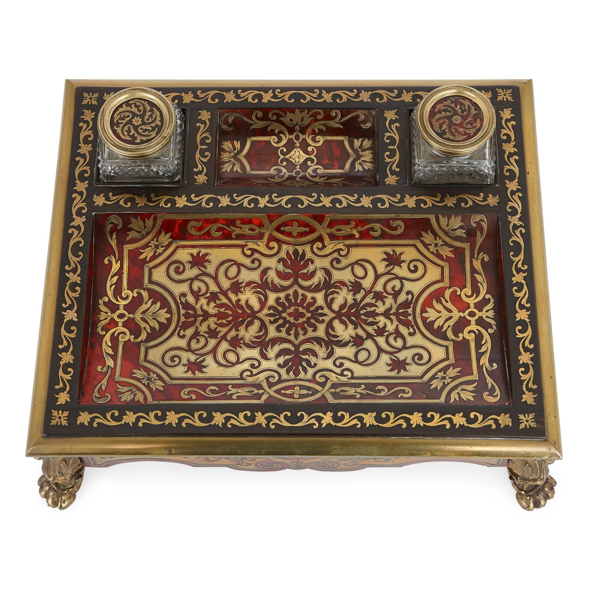 This antique English inkstand was crafted in the 19th century in ormolu and tortoiseshell using the technique of marquetry made famous by the French cabinetmaker Andre Charles Boulle.
The inkstand takes a rectangular shape, set on four gilt bronze