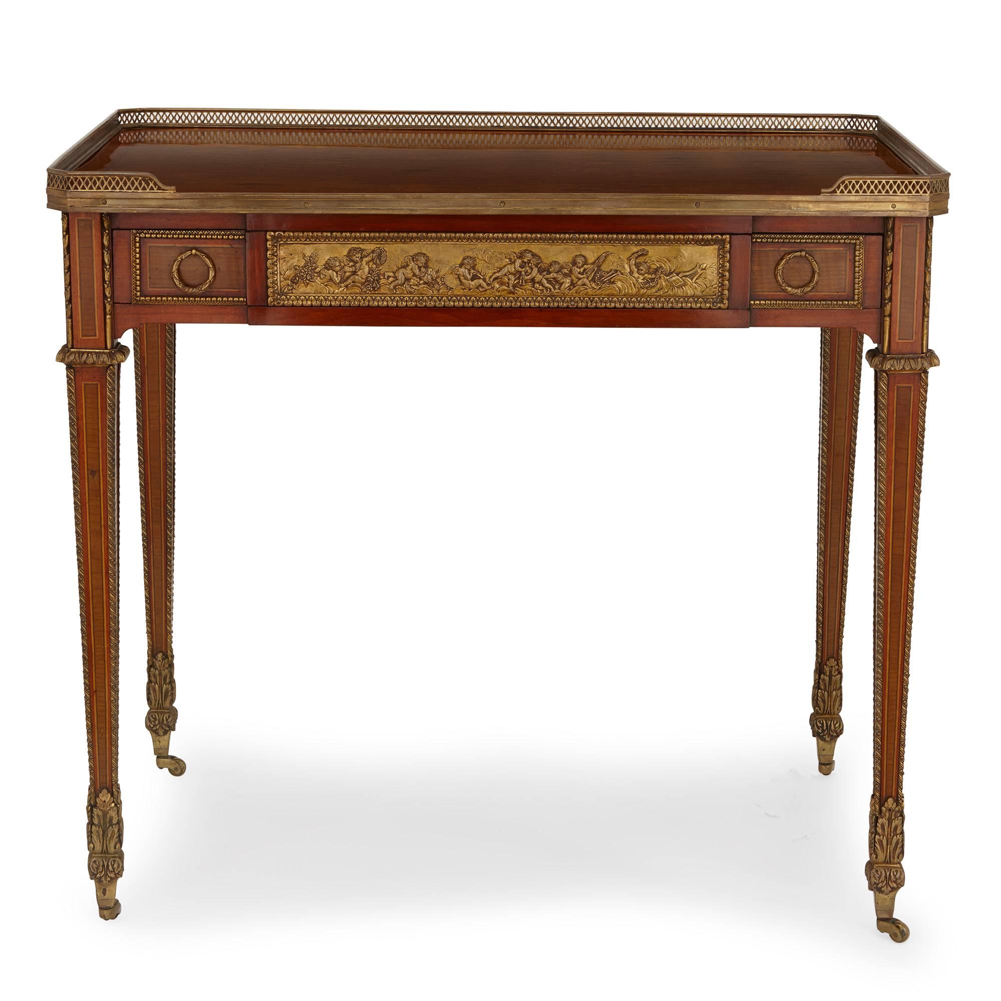 This antique ormolu-mounted writing table was crafted with intricate parquetry detailing, and was built after the model by celebrated French maker Jean-Henri Riesener (1734-1806). Riesener was a favourite maker of Queen Marie Antoinette, and this