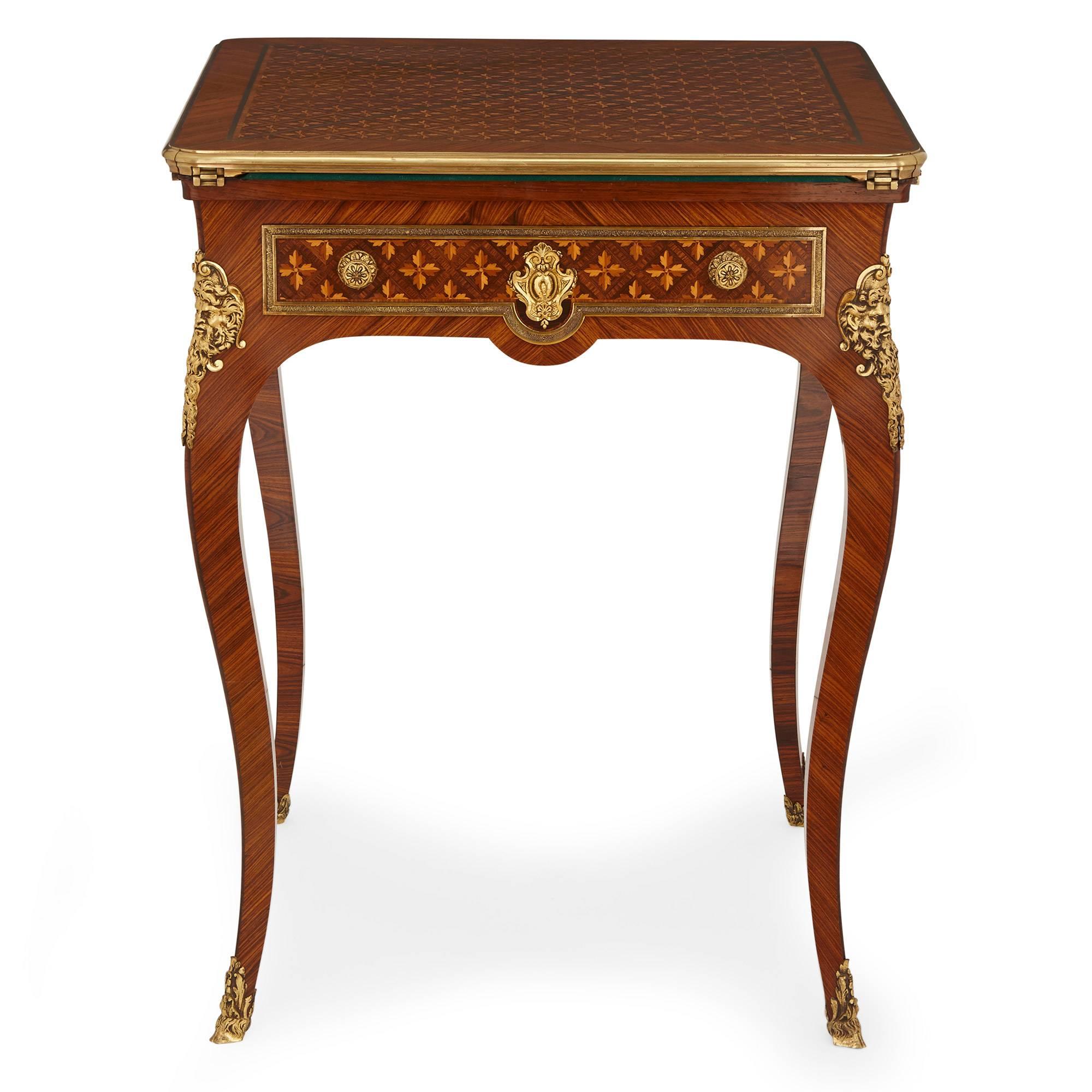The top of this fine, antique folding card table features a parquetry pattern of acanthus leaves in contrasting rosewood, kingwood and fruitwood. The tabletop is mounted in ormolu around the edges and folds outwards to open into a green baize