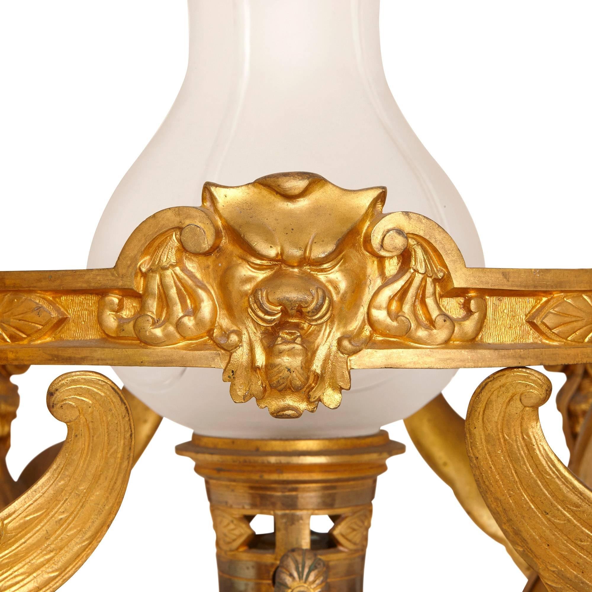 This beautiful antique French chandelier dates from the 19th Century and could be attributed to the master bronzier Ferdinand Barbedienne. It is cast entirely in gilt bronze, and features Empire style and neo-Grec ornamentation all over. The base of