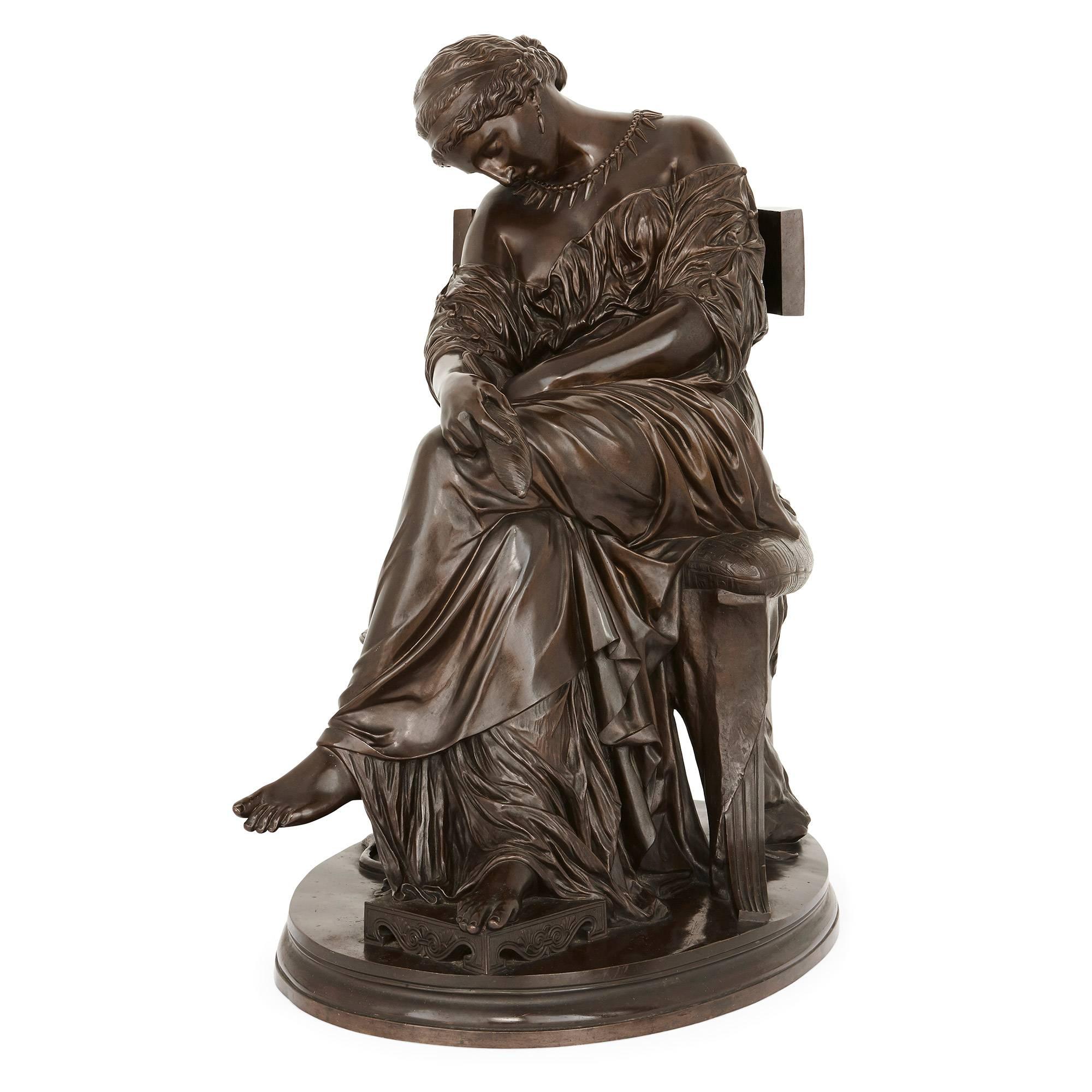 This large patinated bronze antique sculpture depicts the Classical figure Penelope, the wife of Odysseus (Roman name Ulysses) who appears in Homer's Odyssey. The sculpture is set on an oval base and Penelope is shown sleeping on a chair with a