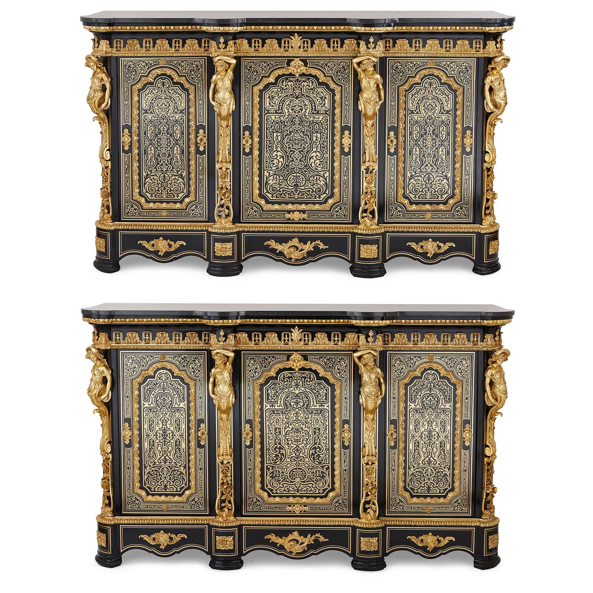 Each of the cabinets features a black marble top, which sits above a very finely detailed ebonized wood cabinet case. The front of each cabinet has three panelled doors, flanked on each side by four ormolu mounts in the form of female figures, and