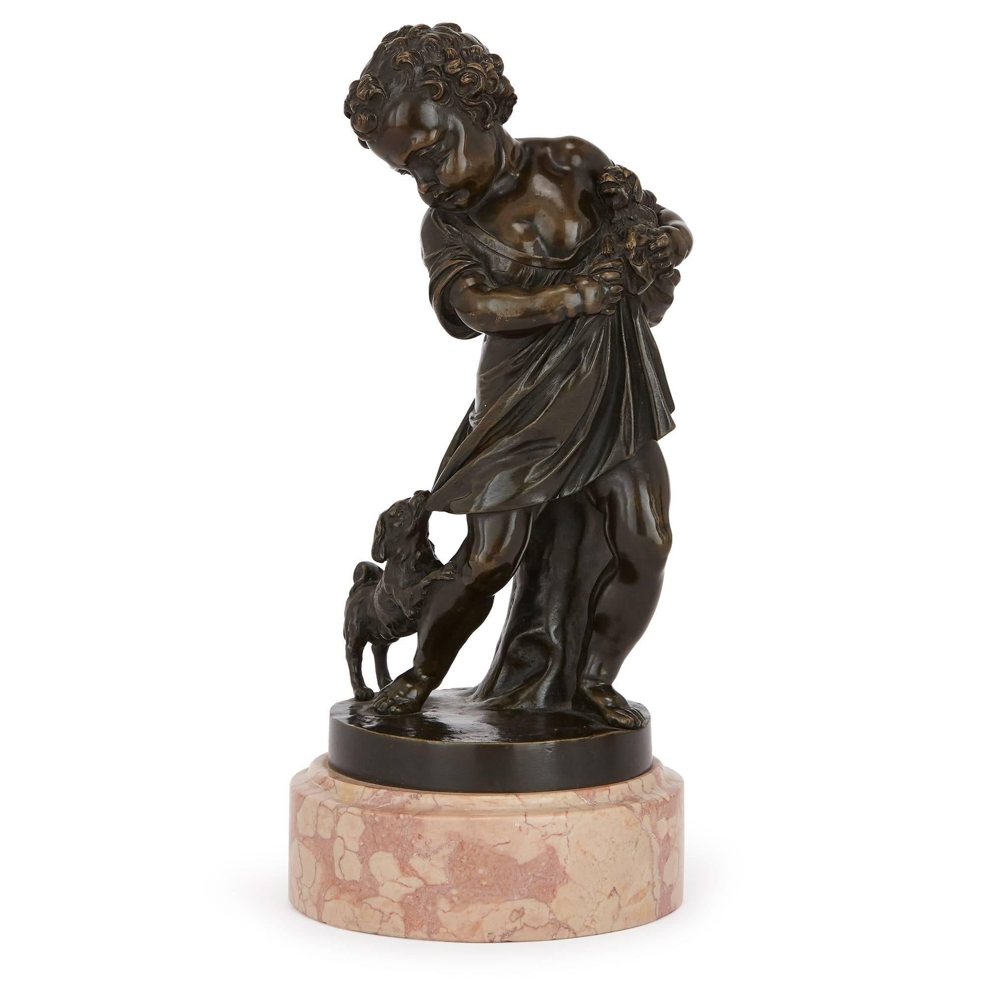 Full of humour and narrative detail, this joyous set of two figural sculptures are charmingly cast in bronze to depict young boys playing with animals. One of the figures shows a boy in draped clothing holding a dog to his chest, while another dog