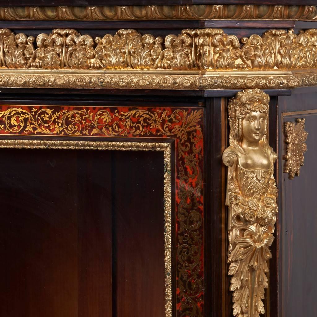In the Louis XIV style, the tortoiseshell and brass inlaid ebonized wood body, with three wooden shelves, the front with glazed doors, surmounted with a white marble top.