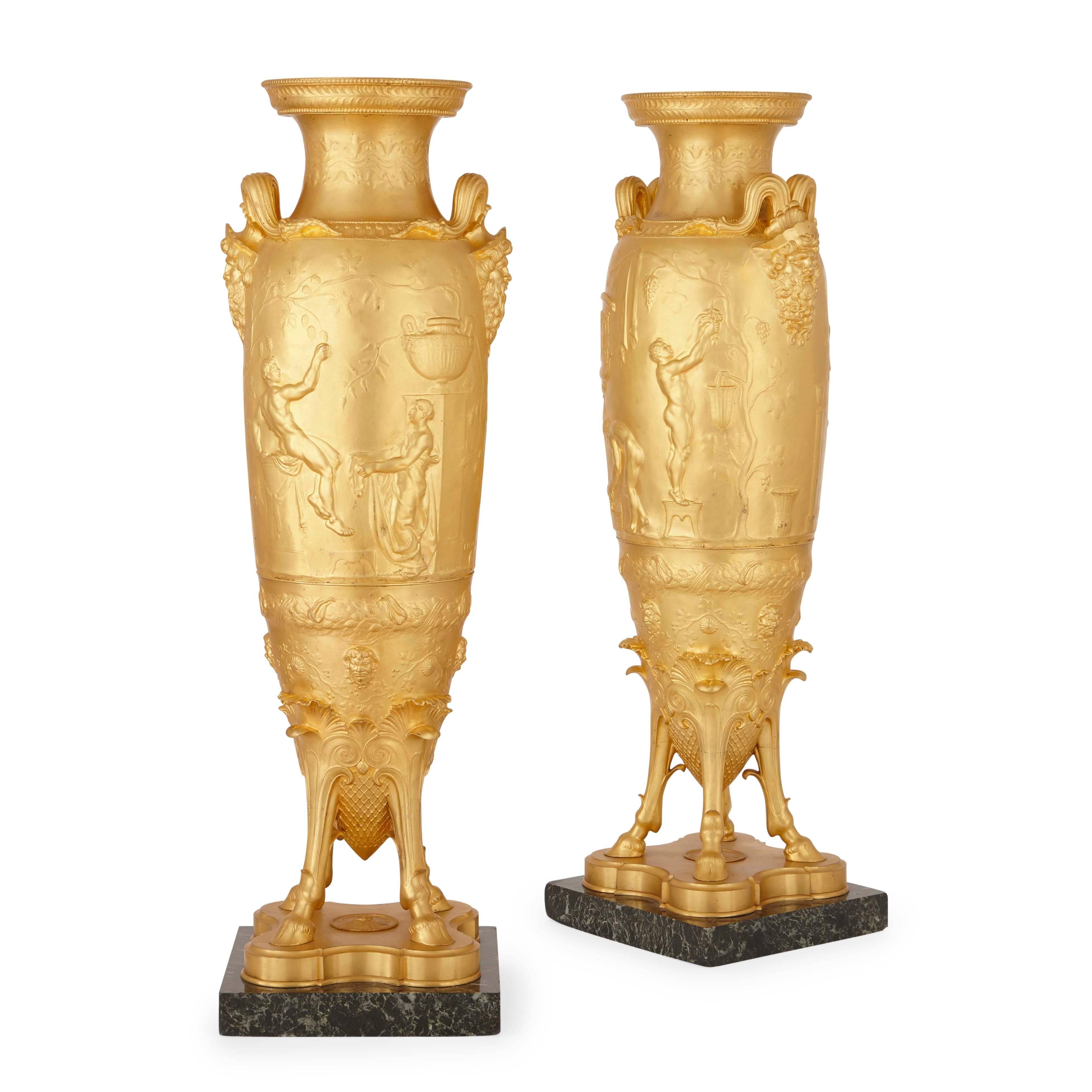 The exquisite gilt bronze (ormolu) vases decorated with alternating scenes of harvesting and portraits of Ariadne and Bacchus, each vase with twin handles terminating in male busts, the bases with four hoof feet and set on square veined marble
